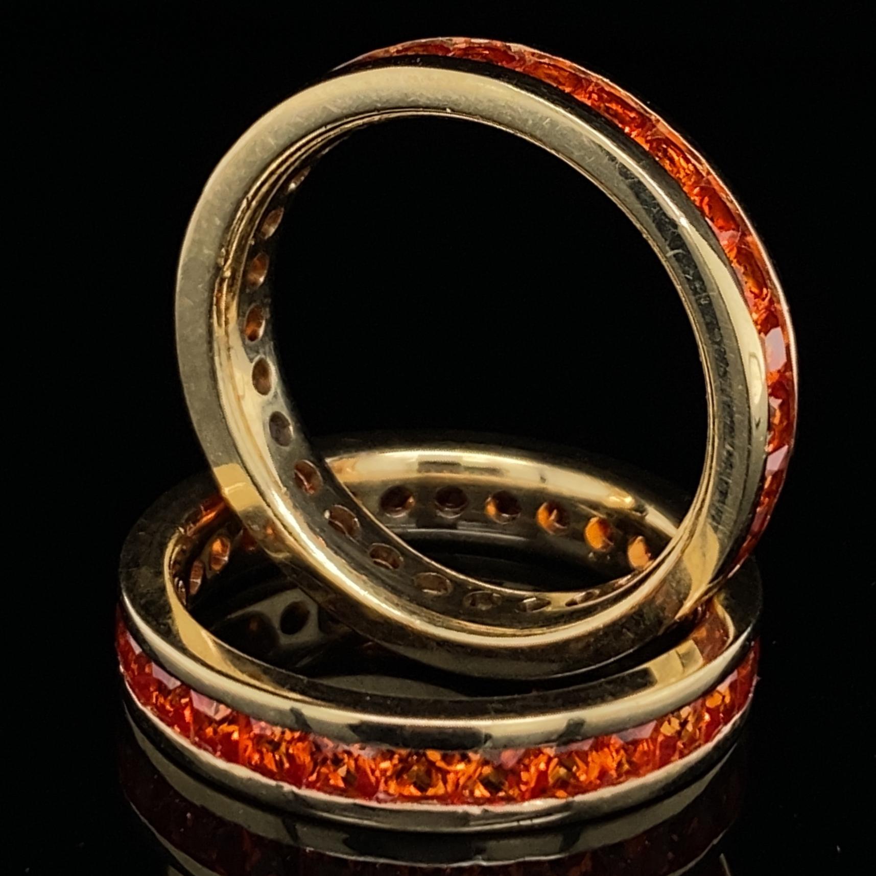 Eytan Brandes presents a versatile and intensely colorful pair of orange sapphire eternity rings.

Instead of round stones, Eytan chose squares with a cut similar to diamond princess cuts.  Square stones are a great choice for channel-set eternity