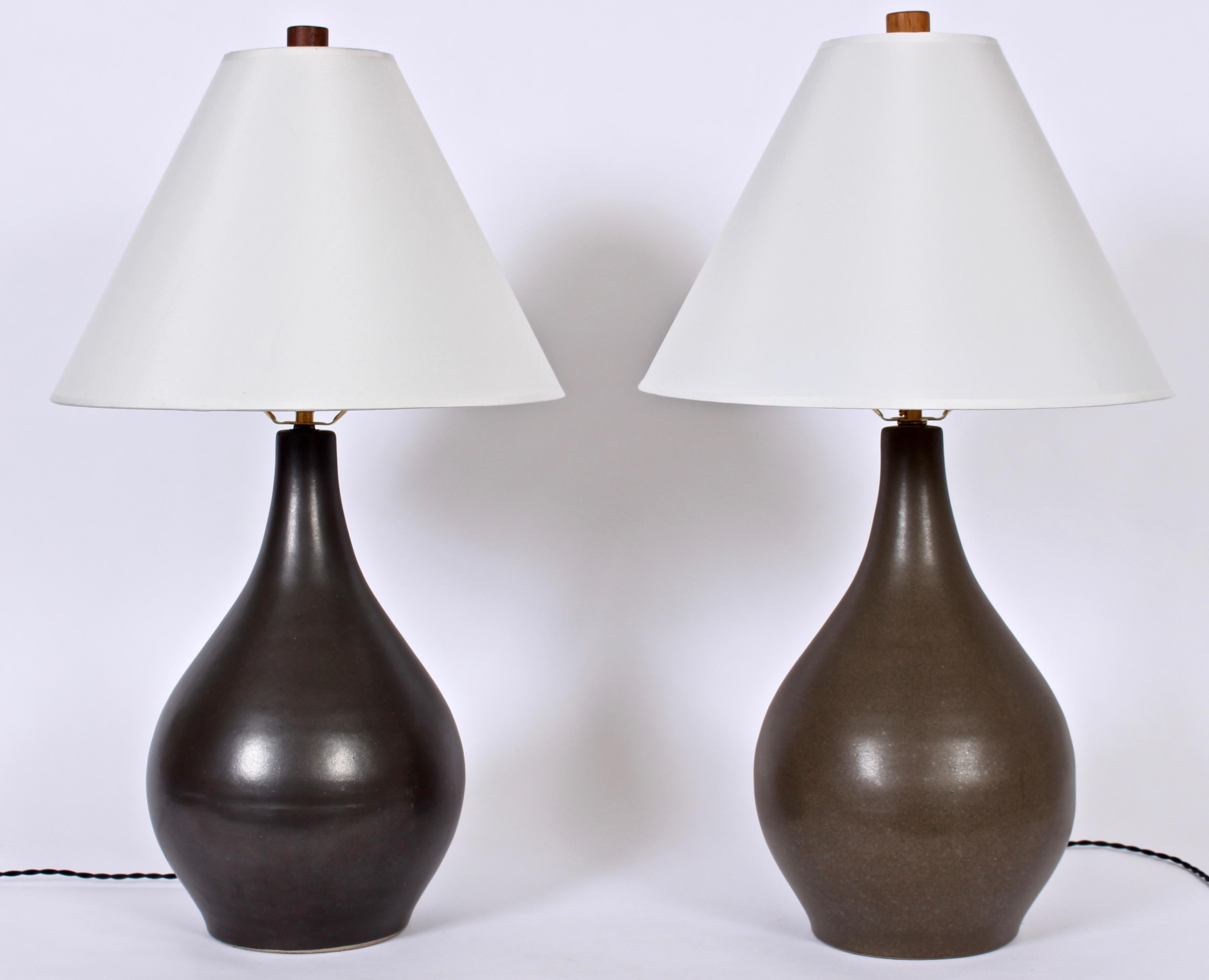 Two American Mid-Century Modern handcrafted Martz stoneware lamps. One lamp featured in Gun Metal, and second in Dark Taupe, each with matte glaze and original wood finials. 18 H to top of sockets. 15 H to top of Ceramic. Shades shown for display