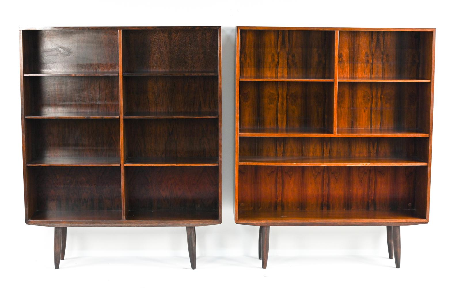 Two Scandinavian mid-century modern bookcases on tapered legs designed by Gunni Omann for Omann Jun, 1960's. Both in rosewood with adjustable shelf height positions. These bookcases have slightly different shelf configurations and finishes, but are
