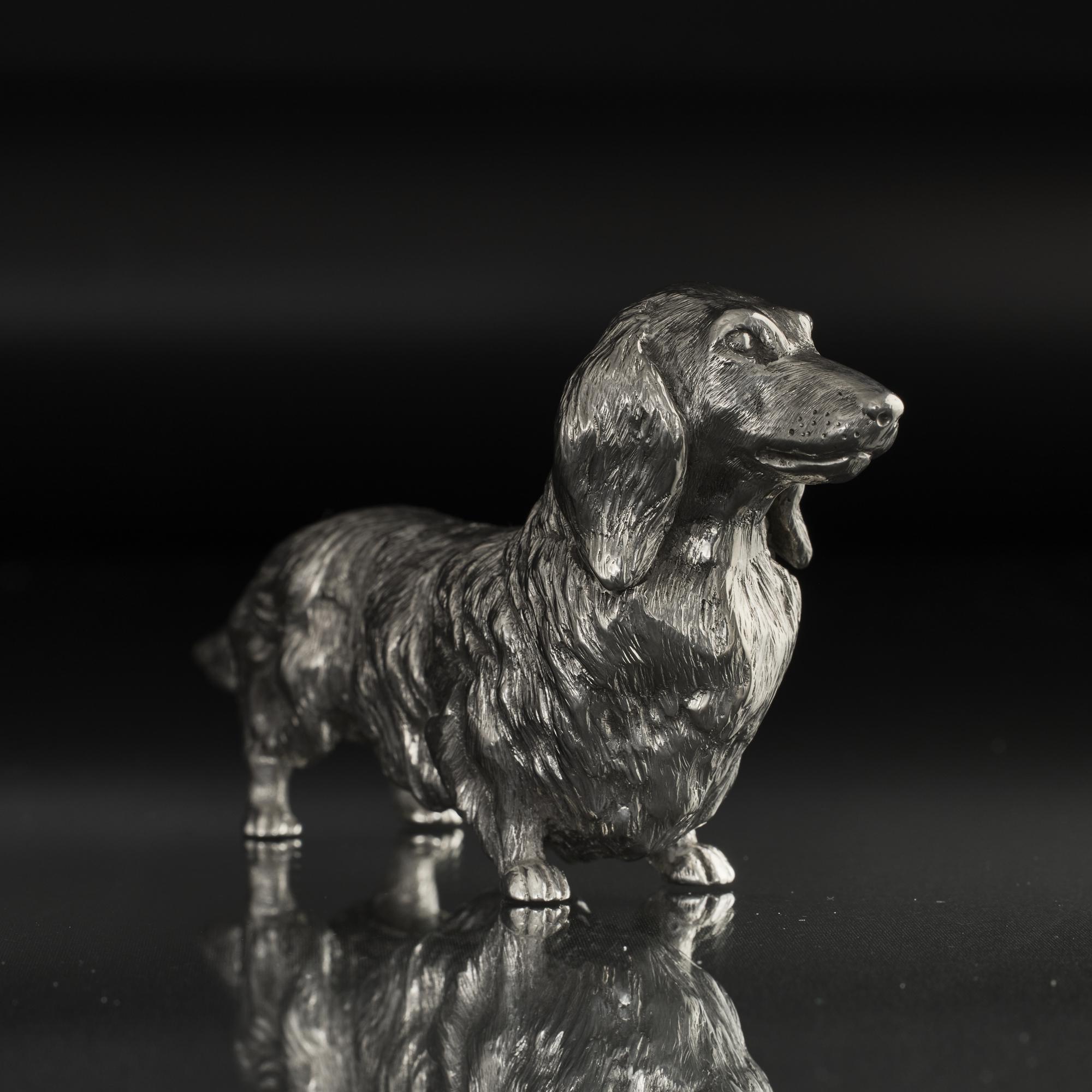 Finely detailed and charming model of a long-haired dachshund dog in solid, cast and hand chased silver and showing all the key characteristics and proportions of this much loved breed. 
 
 Colloquially known as sausage dogs, the name dachshund is