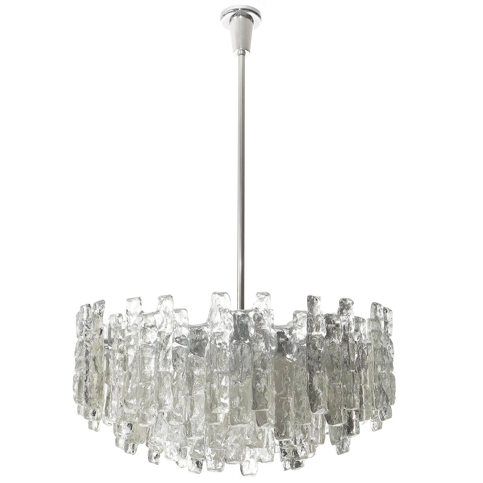 One of two extra large light fixtures model 'SORIA' by Kalmar, Austria, manufactured in midcentury, circa 1970 (late 1960s-early 1970s). These chandeliers are the largest version of this series.
A silver painted metal frame holds 48 large textured