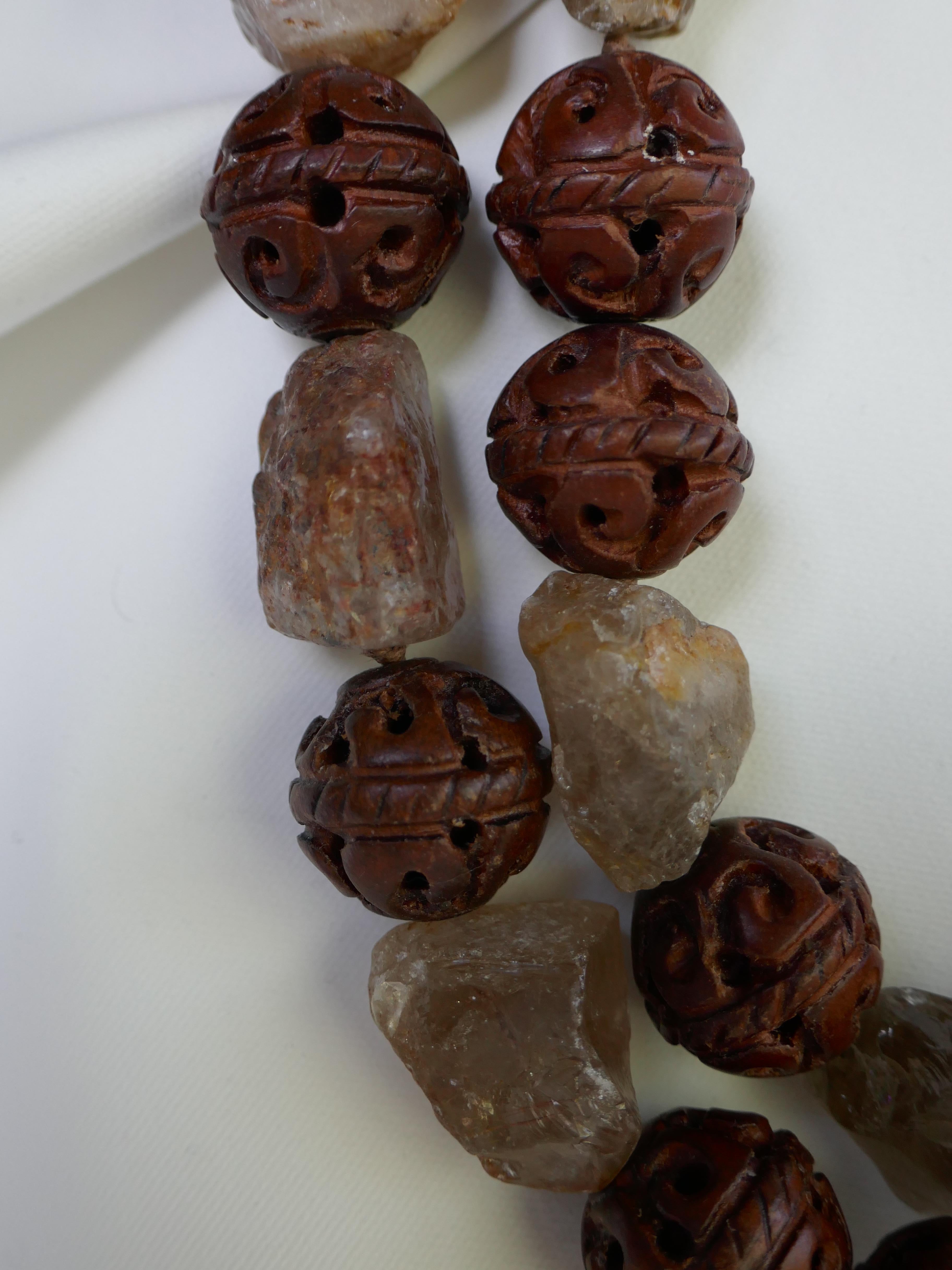 These are two necklace that may be worn together of separately. Worn together they make a stunning statement necklace. The carved wood beads are 20mm and interlace with unpolished Smokey quartz nuggets.  The shorter wood and Smokey quartz necklace