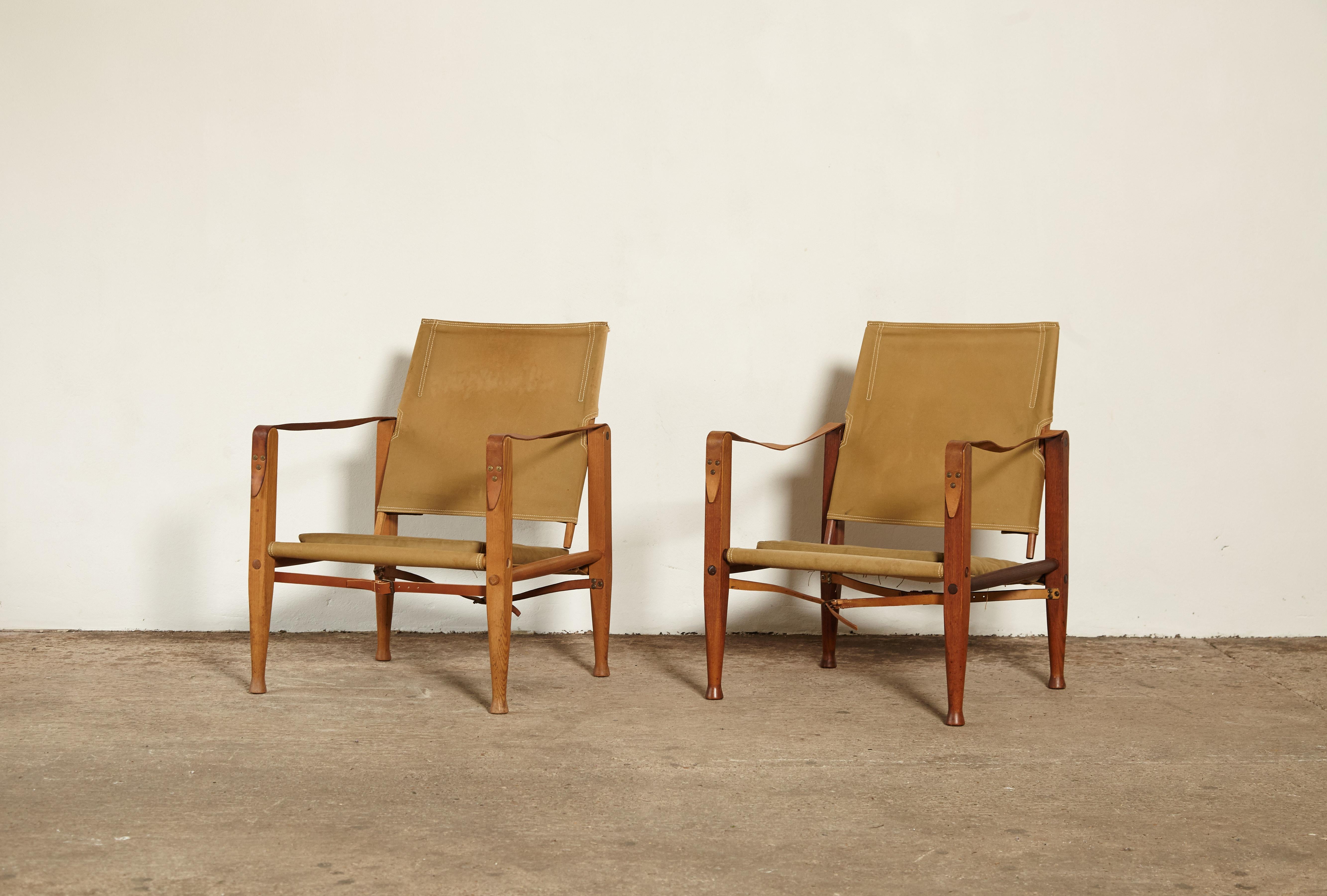 Two Kaare Klint safari chairs, sold as a pair, made by Rud Rasmussen, Denmark. Original olive or khaki canvas and ashwood. Slight variations in tone. Good structural condition but some old marks and stains on canvas as seen in photos. Inexpensive