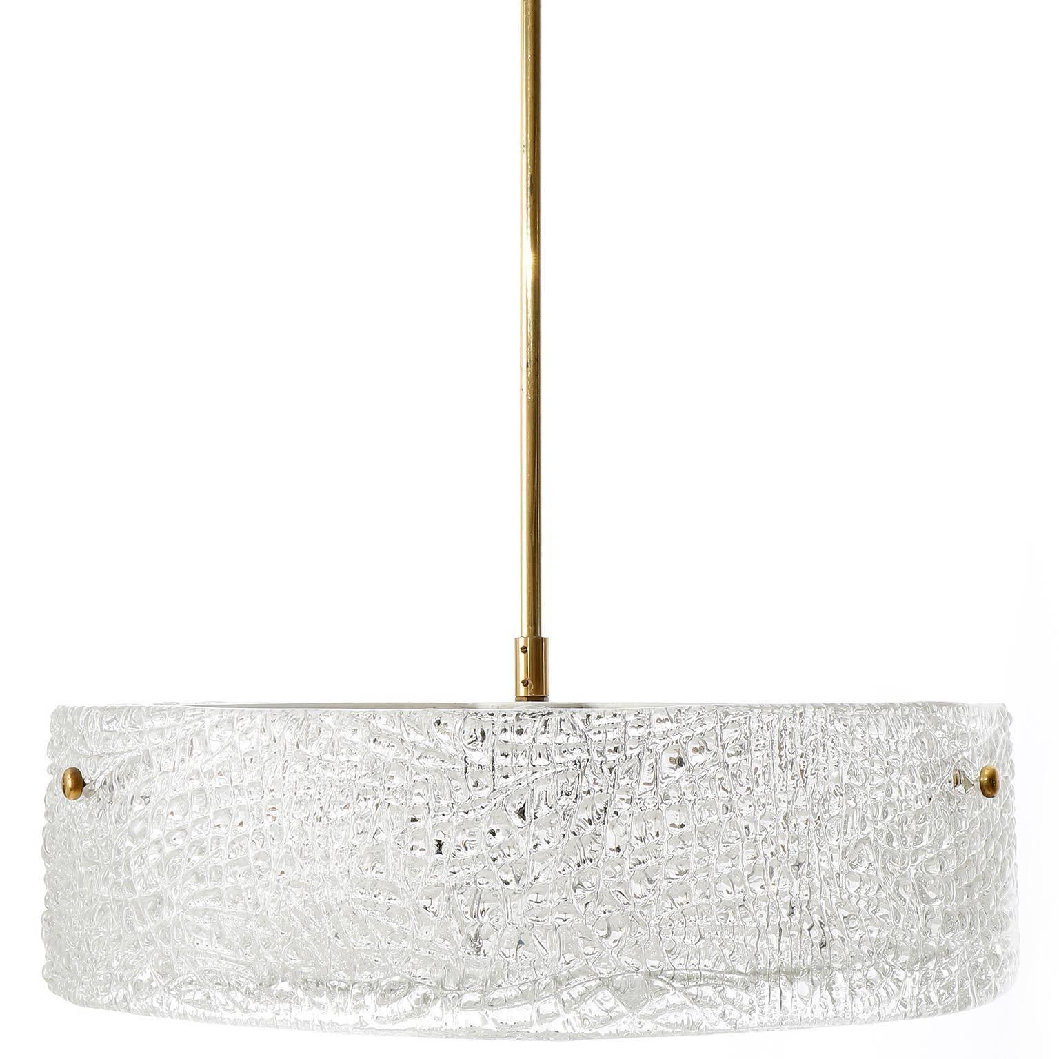One of two beautiful textured glass and brass lamps by J.T. Kalmar, Vienna, manufactured in midcentury, circa 1960 (late 1950s or early 1960s). 
A round glass ring is mounted with three brass bolts on a white enameled metal frame. A textured glass