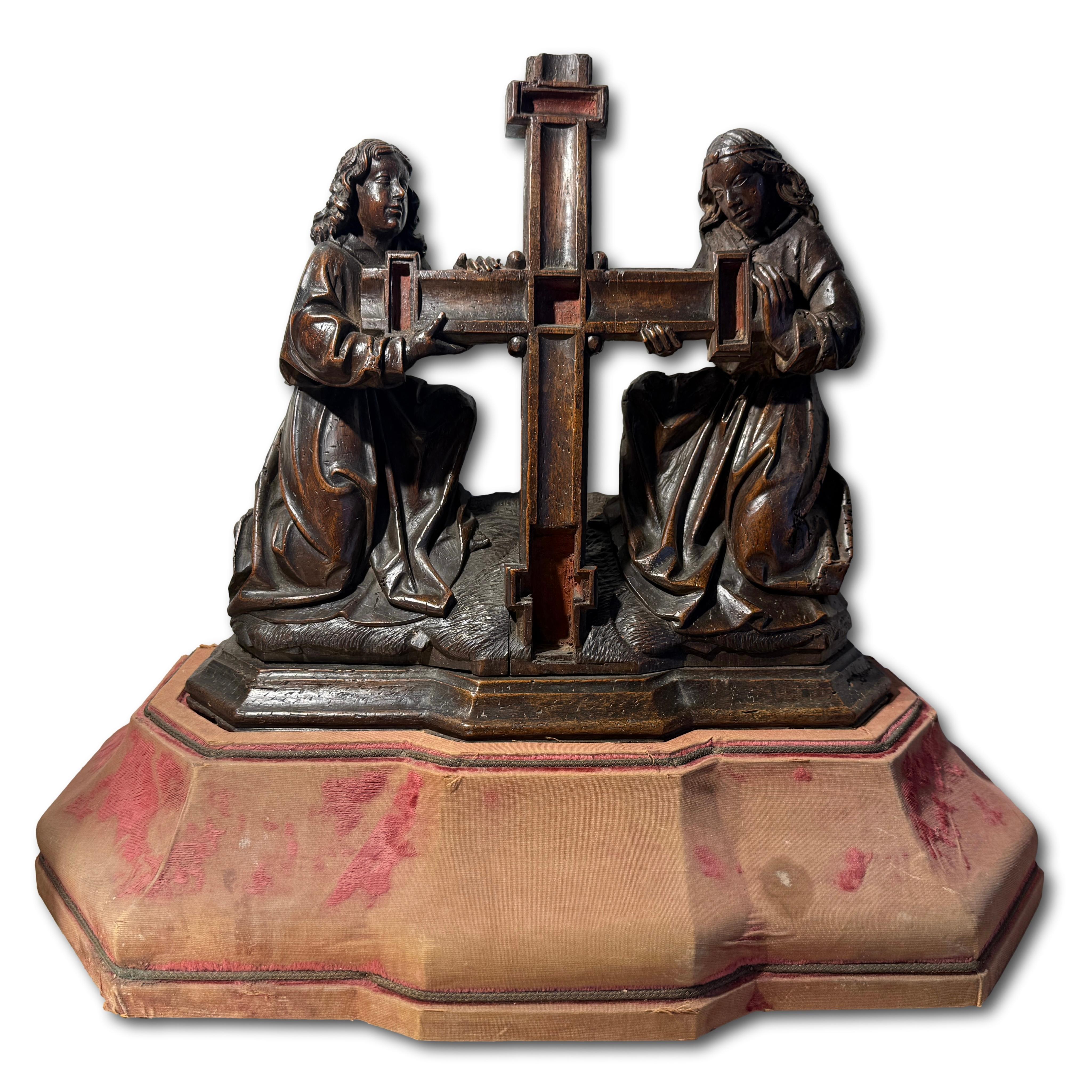 Dos ángeles arrodillados sosteniendo la Cruz.

Sur de Holanda, hacia 1500-1520.

Nogal con restos de policromía original.

Medidas: 37 × 32 × 14 cm (excluido el viejo soporte escalonado de terciopelo rojo).

Grupo gótico tardío finamente tallado que