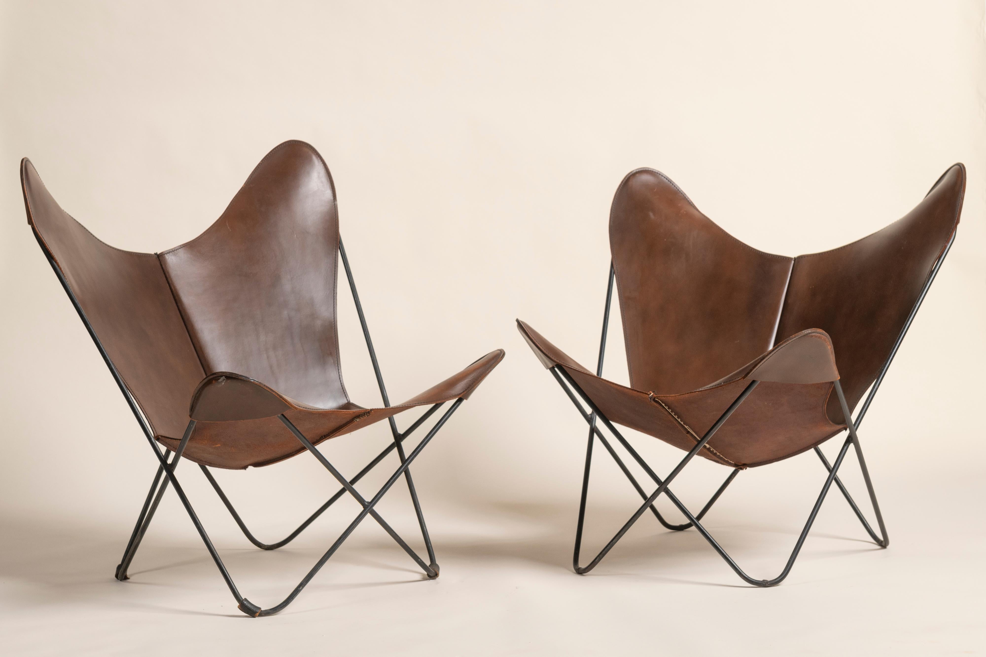 Chaises papillon iconiques d'Icone, vendues à l'unité ou par paire, adaptées à un usage intérieur ou extérieur. Les écharpes en cuir légèrement usé ajoutent au caractère de ces pièces, qui seront appréciées dans tous les contextes.