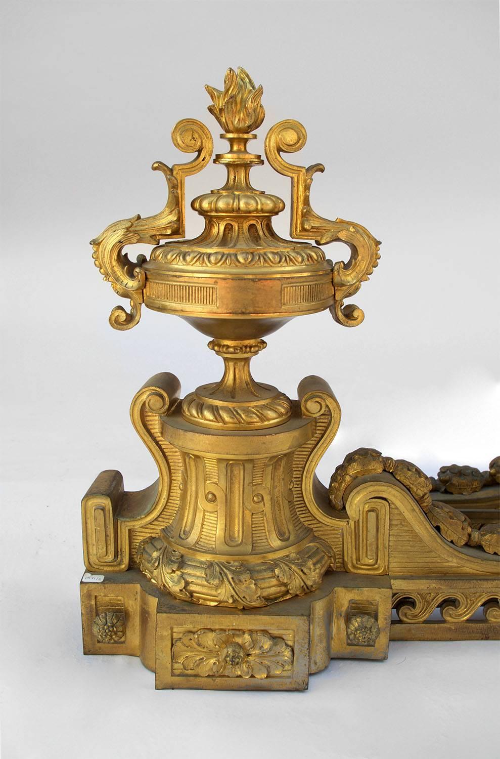 Large pair of chiseled and gilt bronze fire dogs, Louis XVI style.
The upright, adorned with stylized waves frieze, is linked to the front part by a volute with acorns and oak leaves.
The front part is in cassolette-shape topped by a torch and its