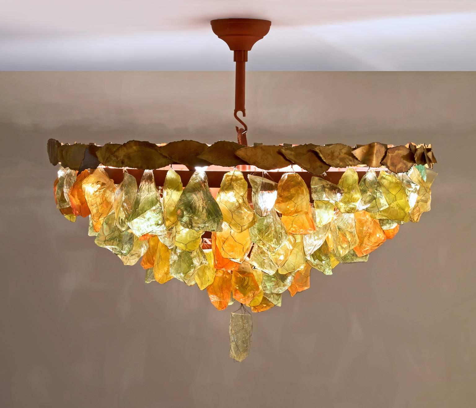 Chandelier, glass, brass, metal, France, 1950s.

This pendant features a diversity of different forms of and colors of glass chunks. The chunks feature autumnal colors. The variety of organic, asymmetrical glass elements is held together with thin