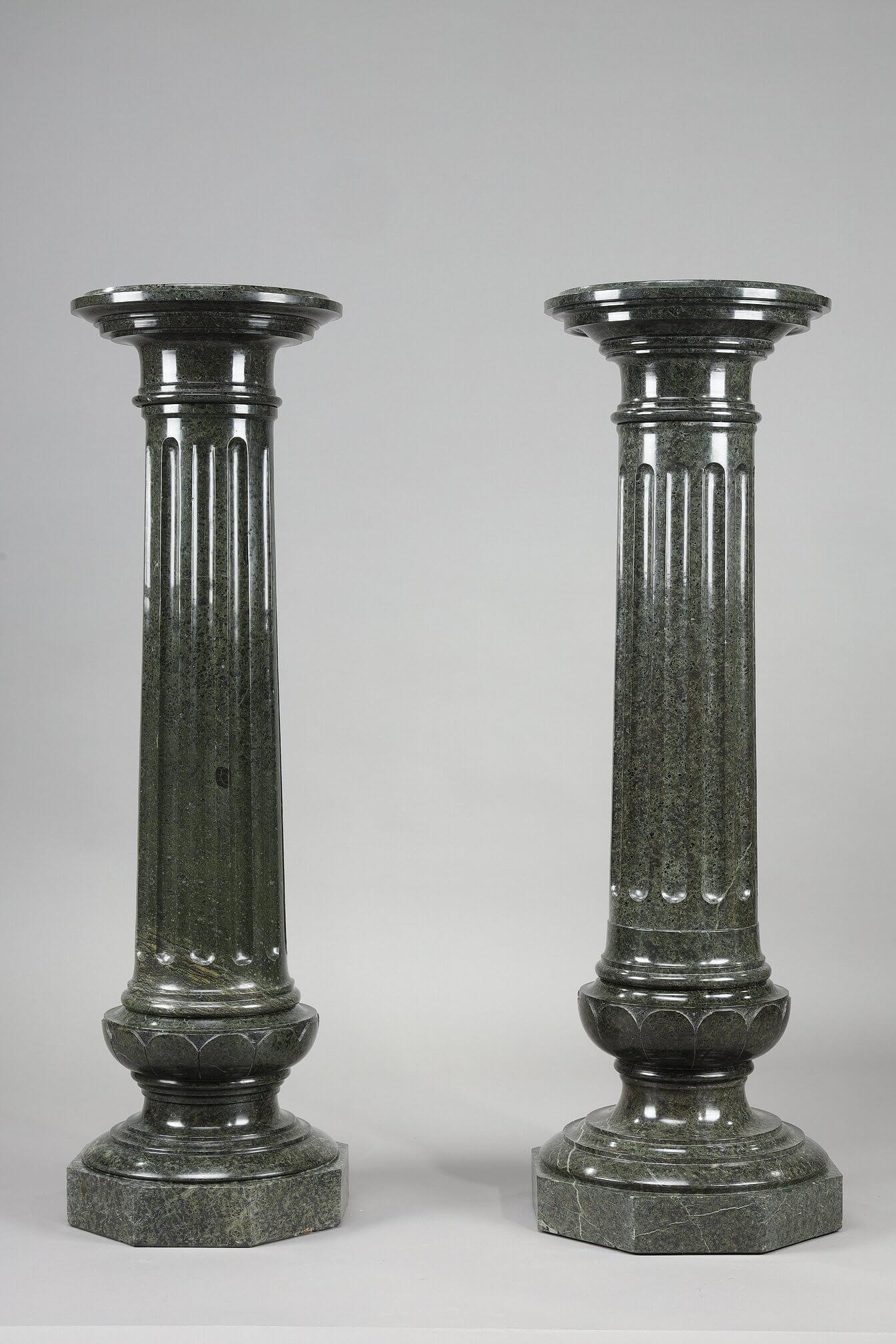 Zwei große Säulen aus grün geädertem Marmor mit breiten Kanneluren, die unterschiedlich geformt sind, aber auch eine Hängevorrichtung bilden können. Achteckiger Sockel.

Abmessung: B: 35cm, T: 35cm, H: 109cm.
Abmessung: B: 13,8in, T: 13,8in, H: