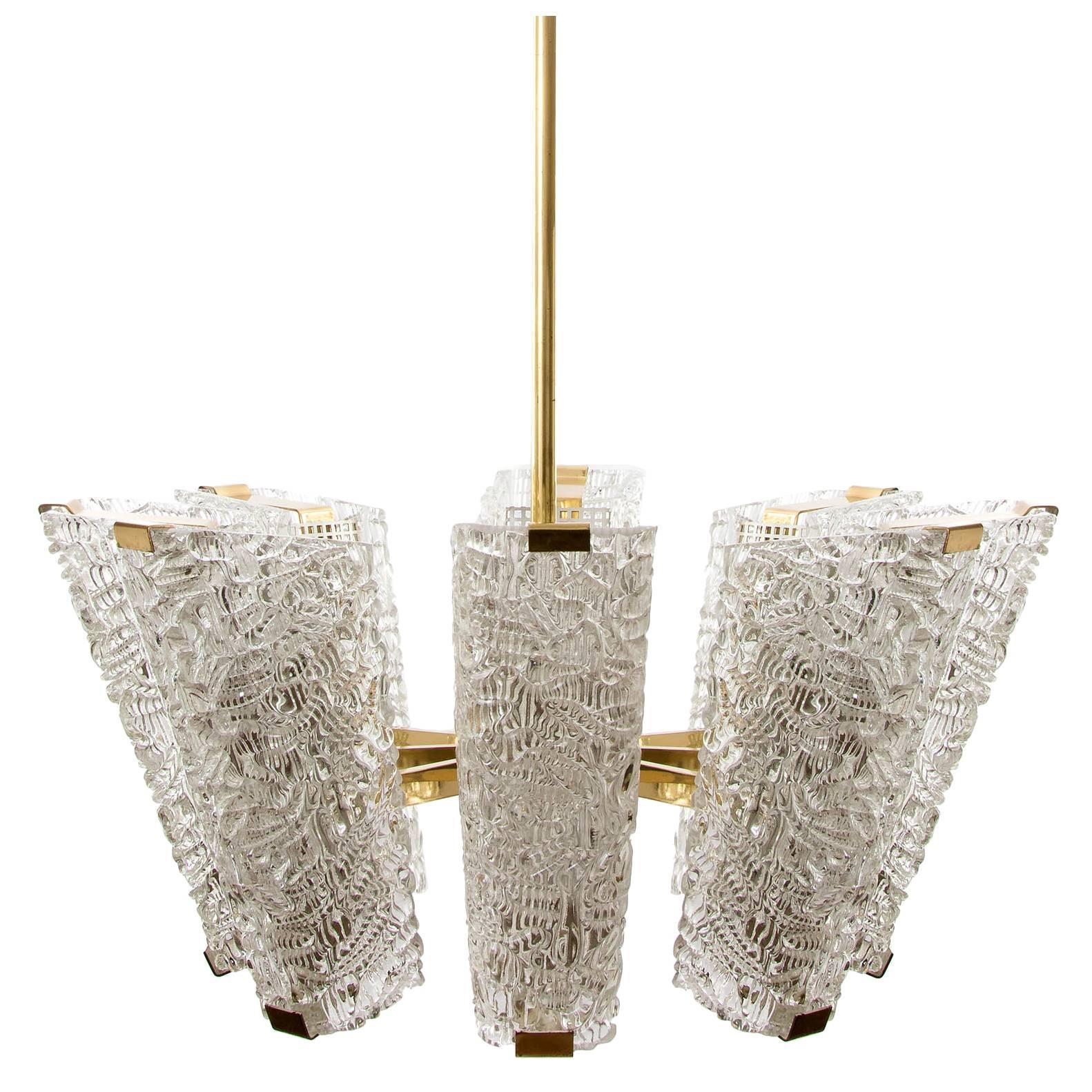 One of two impressive and large chandeliers by J.T. Kalmar, Austria, manufactured in midcentury, circa 1960 (late 1950s or early 1960s).
The fixture is made of polished brass in a warm tone, textured cast glass and perforated white paint metal.
It