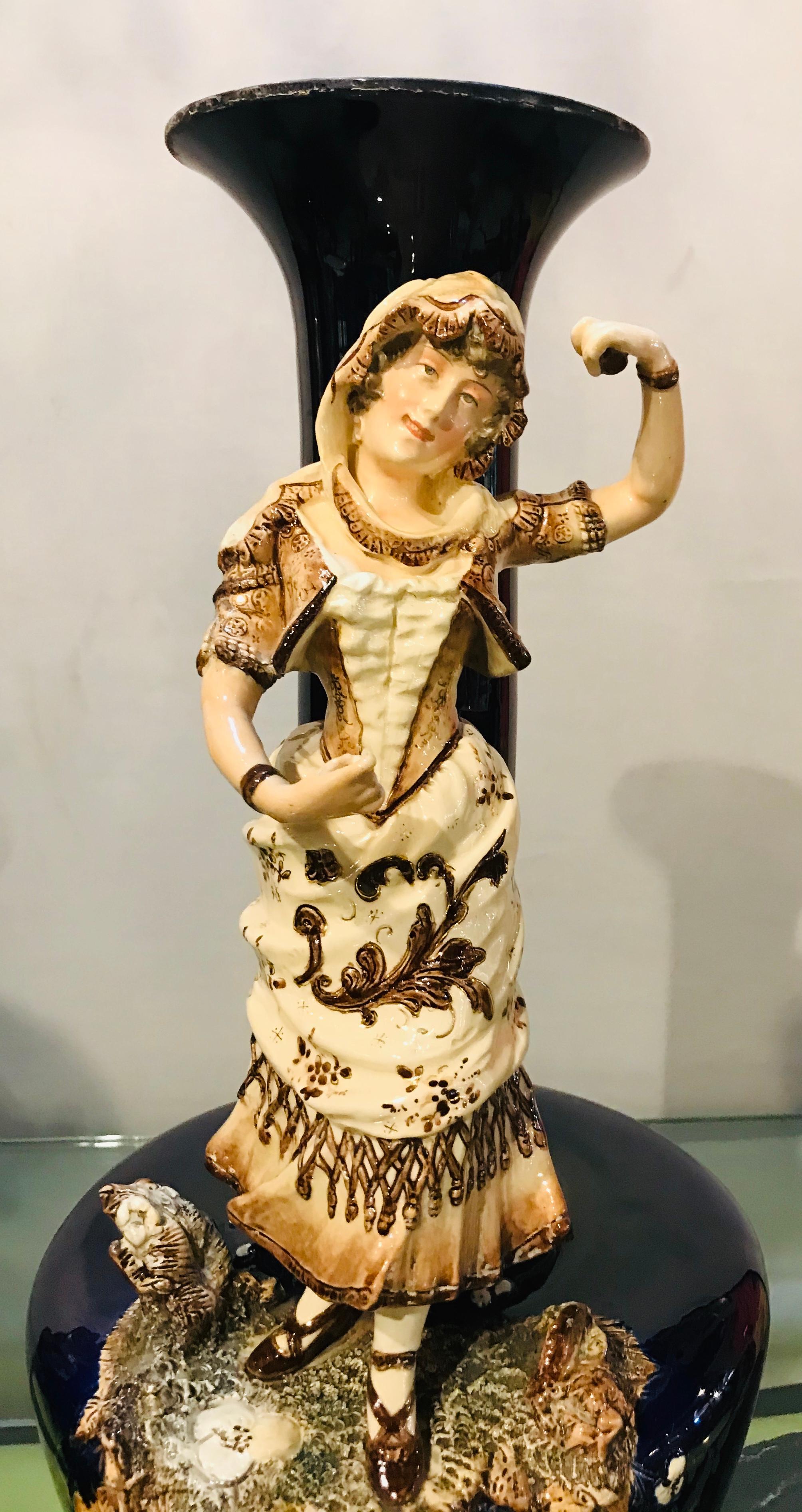 Two large porcelain French 19th-20th century figurative vases or male & female. Dated 1878 and signed on reverse. A finely cast musician and his dancing ballerina mounted on large cobalt blu vases each on a bronze stand.