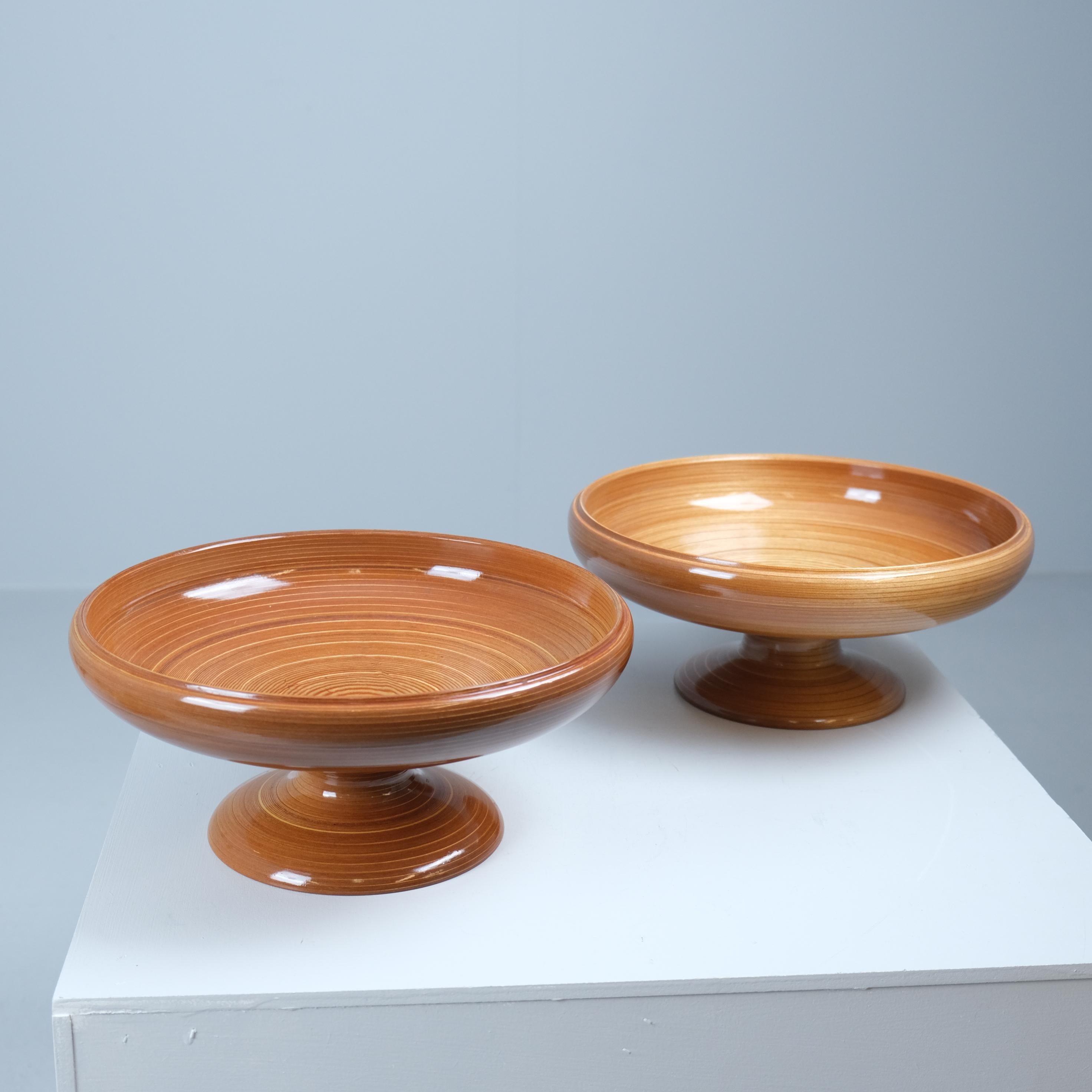 Two large decorative bowls crafted entirely in rhythmic veneer using the classic spinning technique by Wilhelm Schauman Oy, one of Finland’s major mid-century wood and furniture manufacturers. Each bowl comes with a silver presentation plaque on the