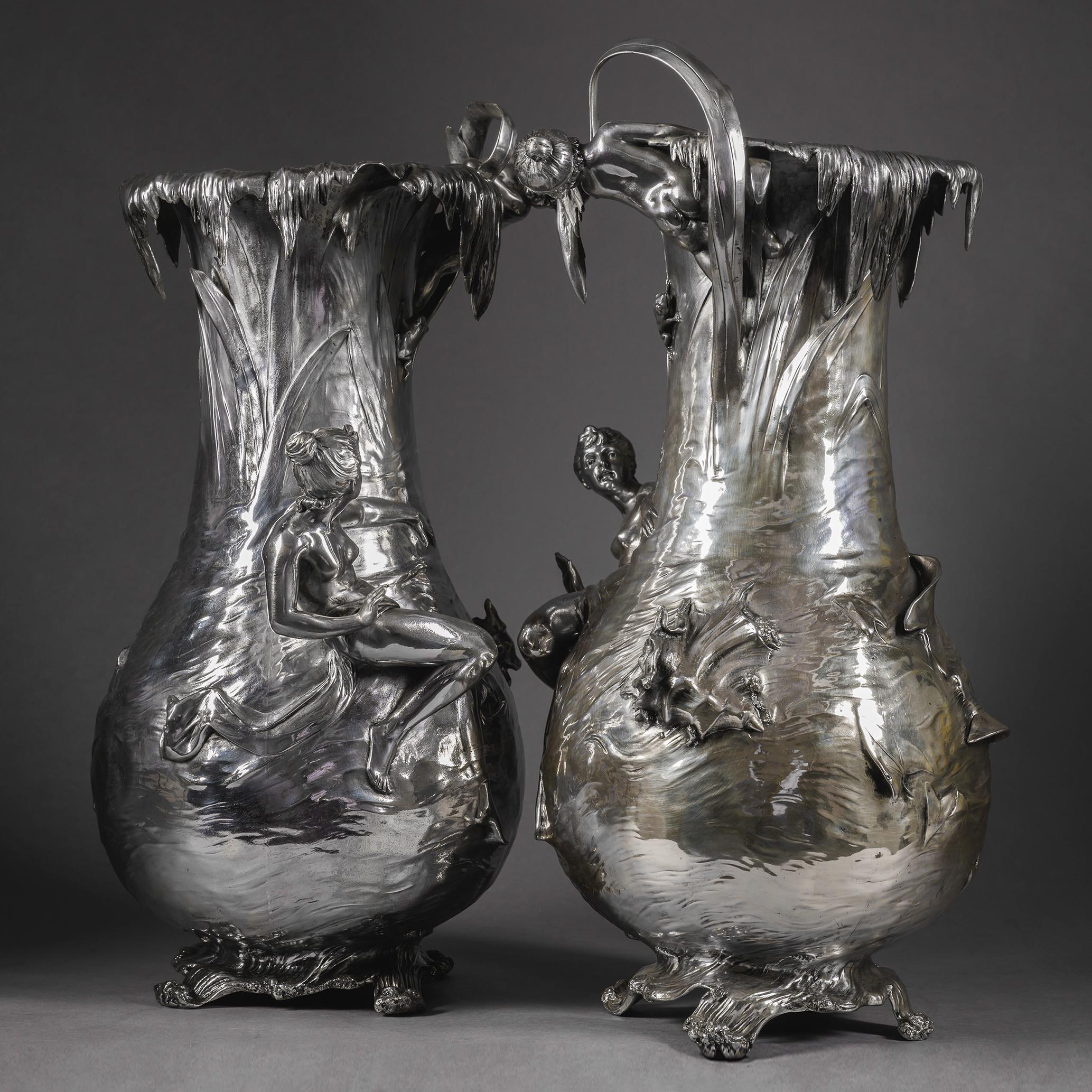 Zwei große versilberte Zinnvasen im Jugendstil, entworfen von Albert Mayer für WMF und geliefert an Adolf Köhler & Cie, Wien.

Jede hat eine bauchige Form und ist mit Wassermotiven modelliert. Wasser, das in Kaskaden von der Lippe herabfließt. Der