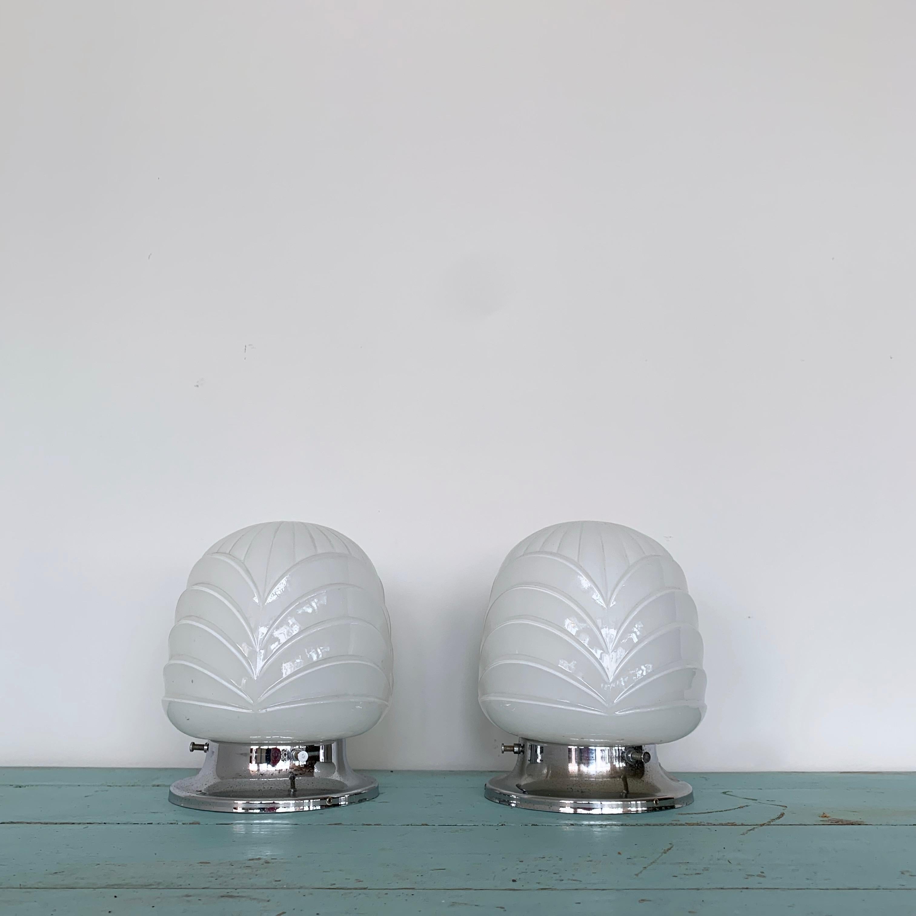 A pair of Art Deco fittings. Pitted aged chromed fittings with scalloped shaped opaline glass shades. Sold as a pair. Can be used as ceiling pieces or wall lights. Each shade requires one B22 lamp.

These have been fully rewired here, in