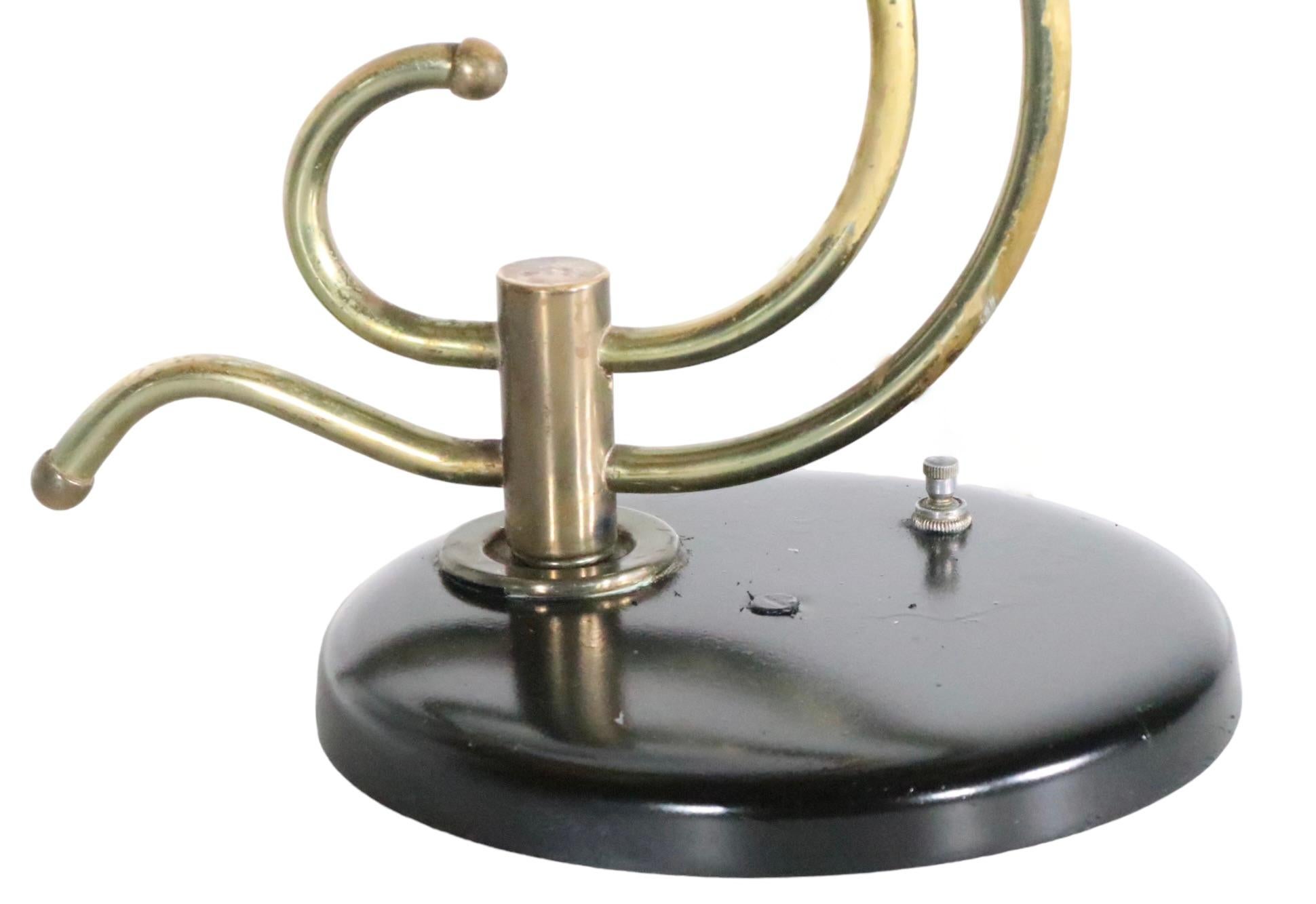 Classic 1950's lighting made in the USA,  by the Majestic Lamp Company.
 The lamp feature two disk form wandering line parchment shades, which attach to the organic  S form brass center post, attached to the black base. The shades tilt up and down
