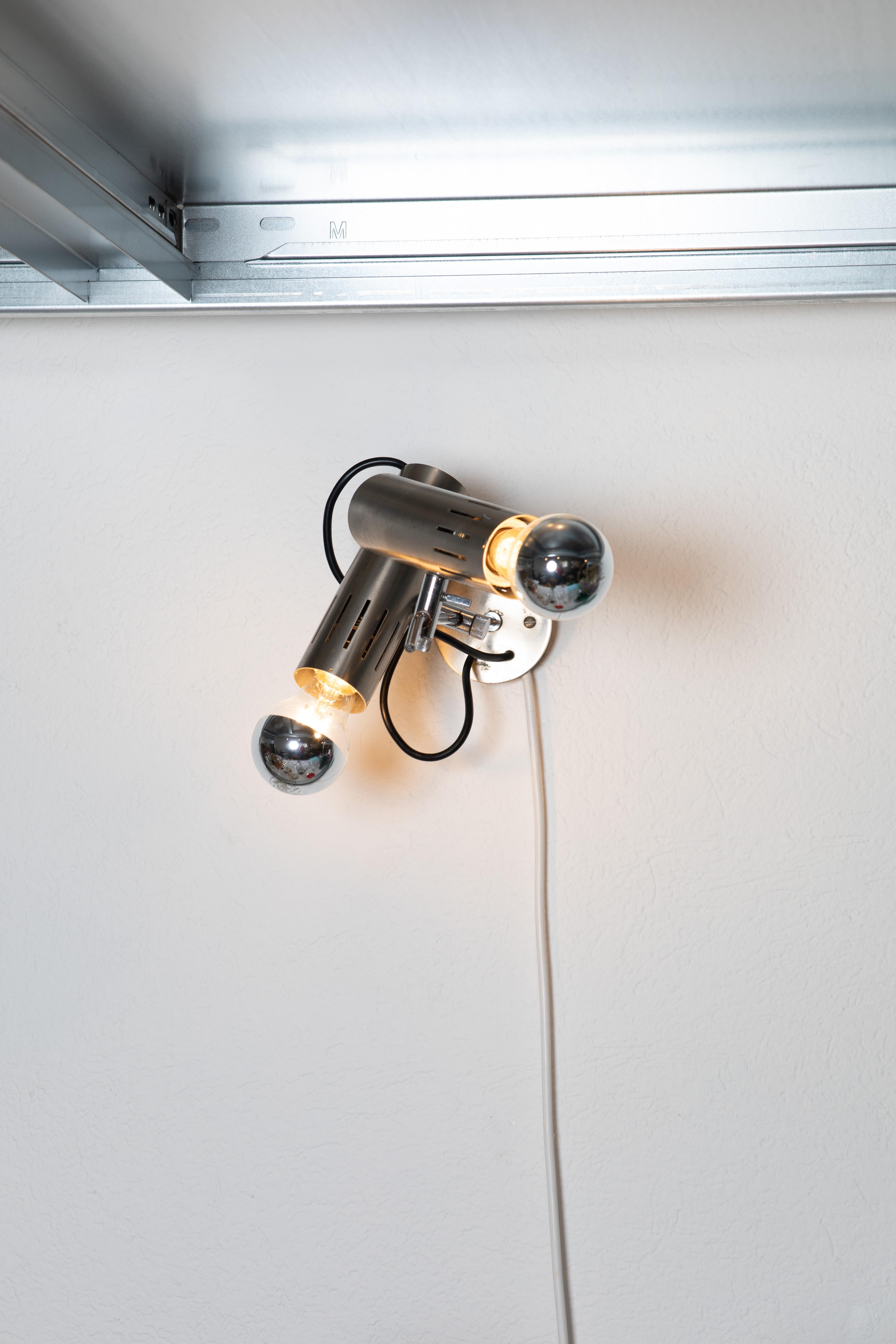 Esta lámpara de pared de dos luces de Alain Richard, diseñada en 1970, es un sorprendente ejemplo de diseño de iluminación moderno. Fabricado en metal cromado, presenta un diseño elegante y minimalista que enfatiza tanto la forma como la función.