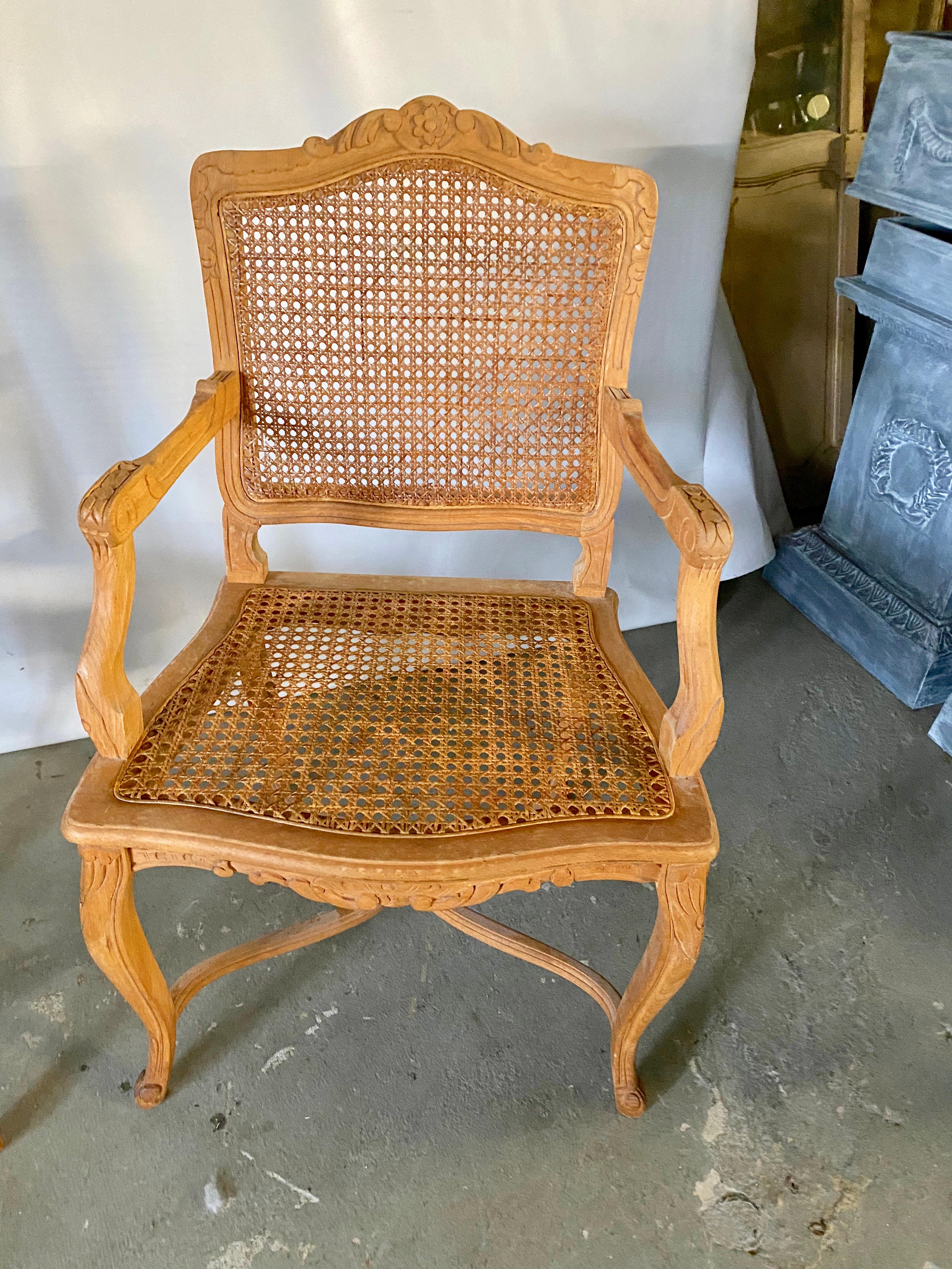 Two antique French country carved pine caned back and seat chairs on cabriole legs, with chair front and crest rail carved with flower and scroll design. The one armchair and one side chair can be sold separately. Both will work well as extra