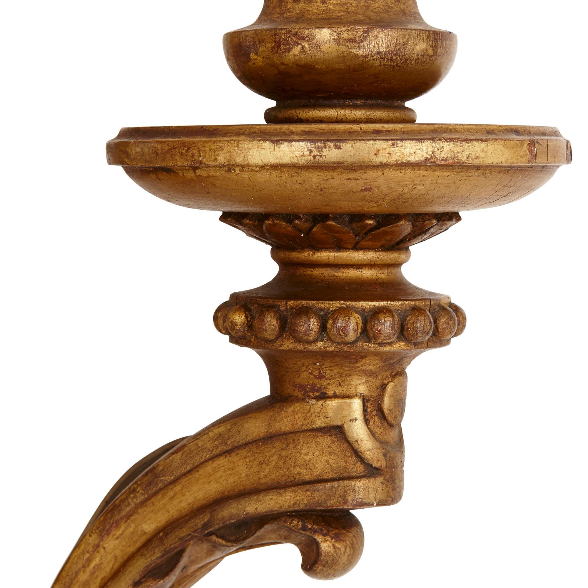 Ces magnifiques appliques en bois doré sont conçues dans le style de l'art décoratif produit à l'époque Louis XVI (1774-1793). Cette période a vu l'émergence du style néoclassique, qui se caractérise par une utilisation parcimonieuse et élégante des