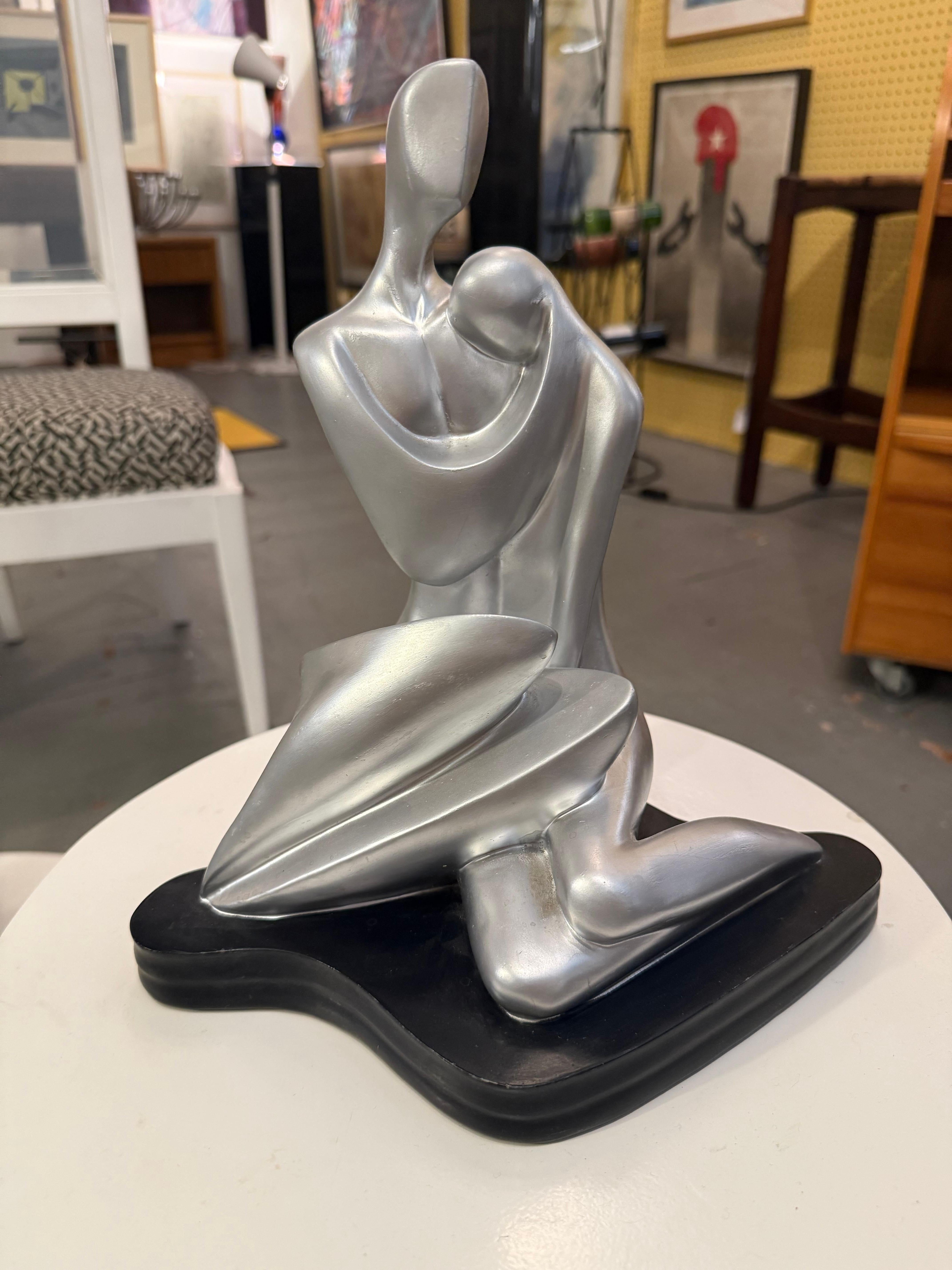 Questa scultura in gesso moderna di metà secolo, rifinita in argento, raffigura due figure astratte in un abbraccio intimo. Le forme morbide e senza volto e le linee fluide catturano sia la tenerezza che la forza, enfatizzando il movimento e l'unità