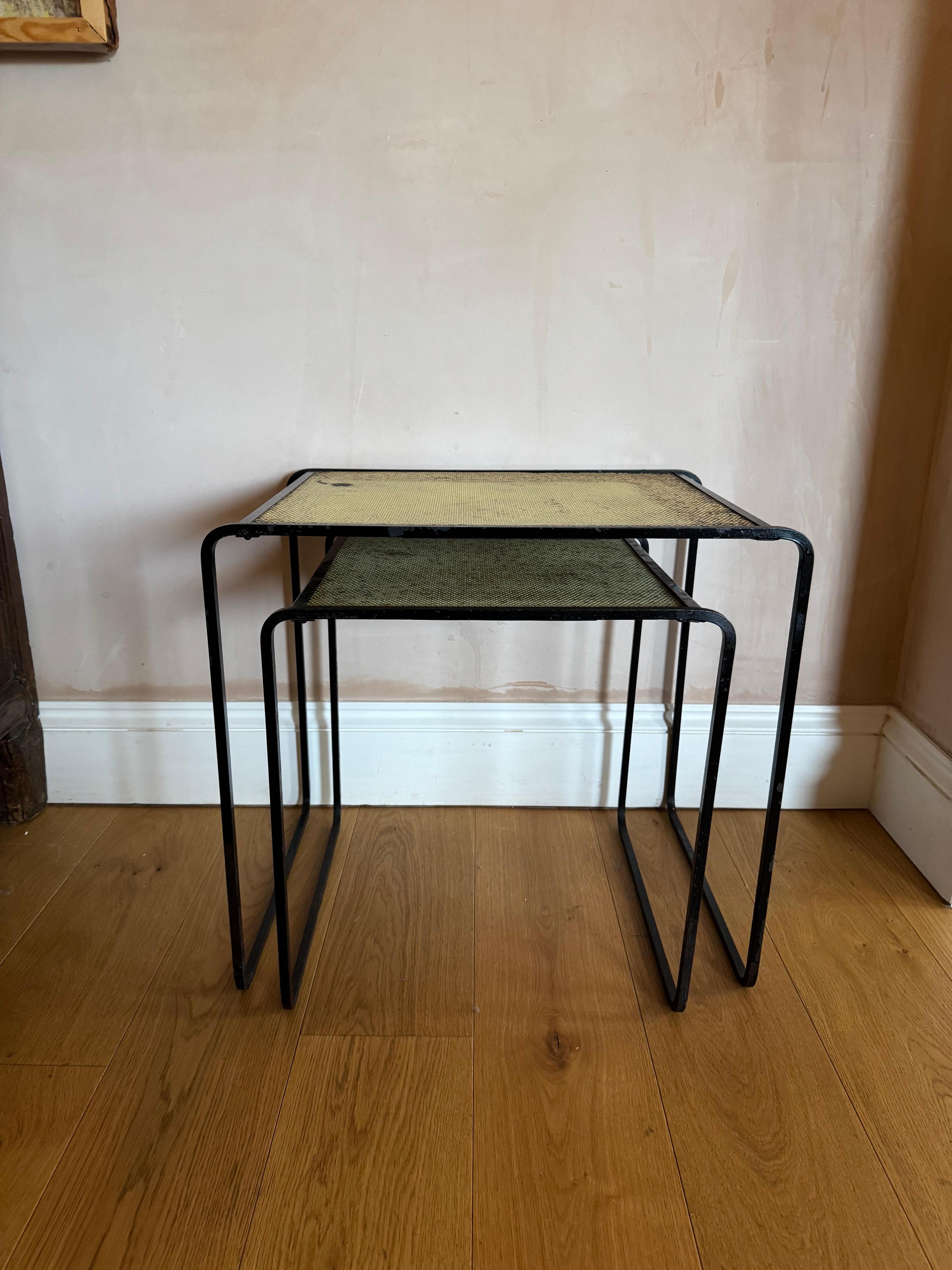 Un set di due tavolini impilabili francesi in metallo traforato degli anni '50. Nello stile di Mathieu Mategot. Vernice originale con perdita di vernice visibile e segni di raggi, ma strutturalmente sana.