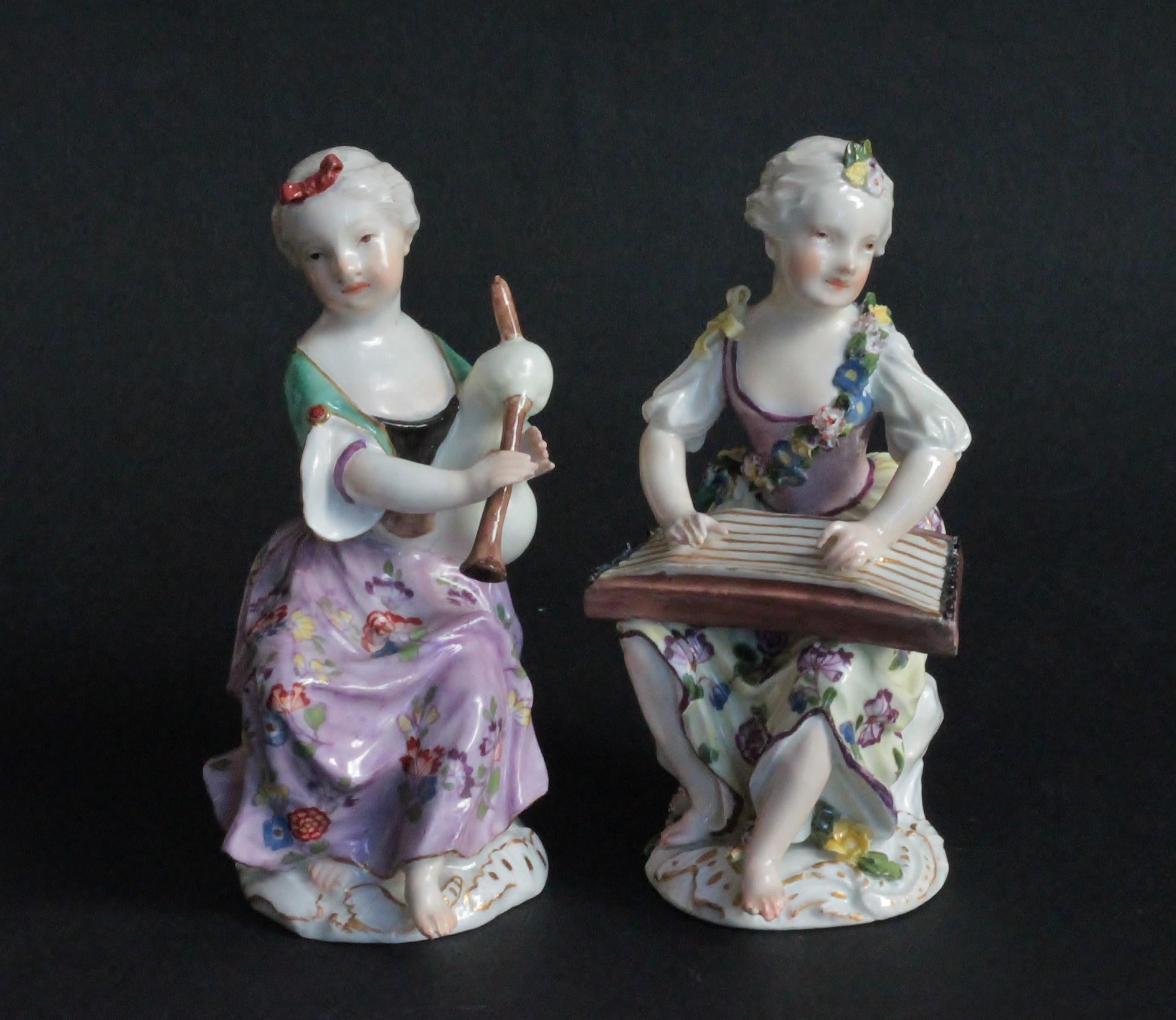 Two Meissen Figures of Young Ladies Playing Instruments, Circa 1755-60.
They are seated with their instruments, zithare and bagpipe, wearing dresses with flowers. The base applied with leaves, flowers and rocailles. Faint traces of crossed swords