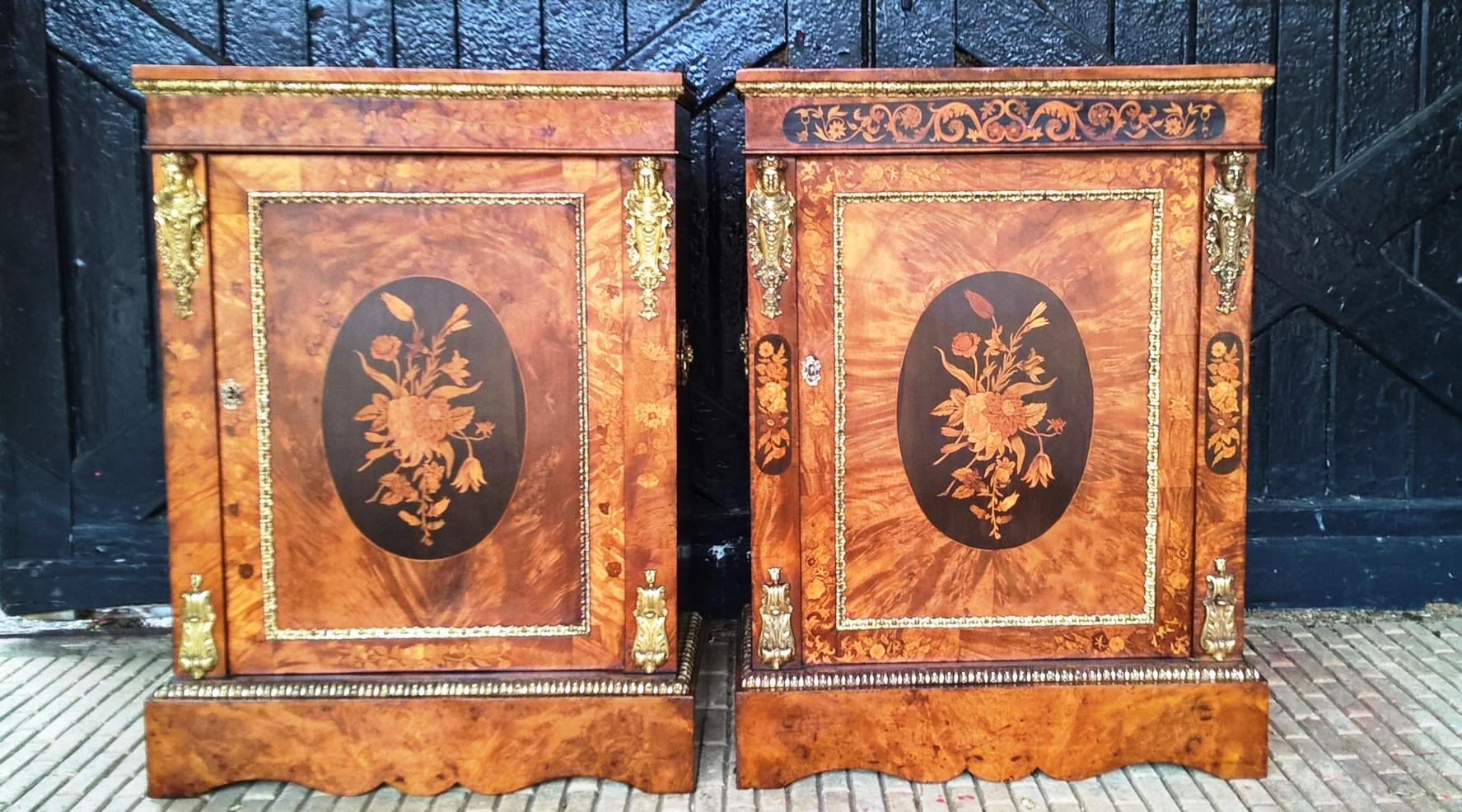 Two very similar metal mounted walnut and marquetry pier cabinets each with folate and floral panels and a central folate and floral display within an oval ebony panel to each door.
Each raised on a shaped plinth base.