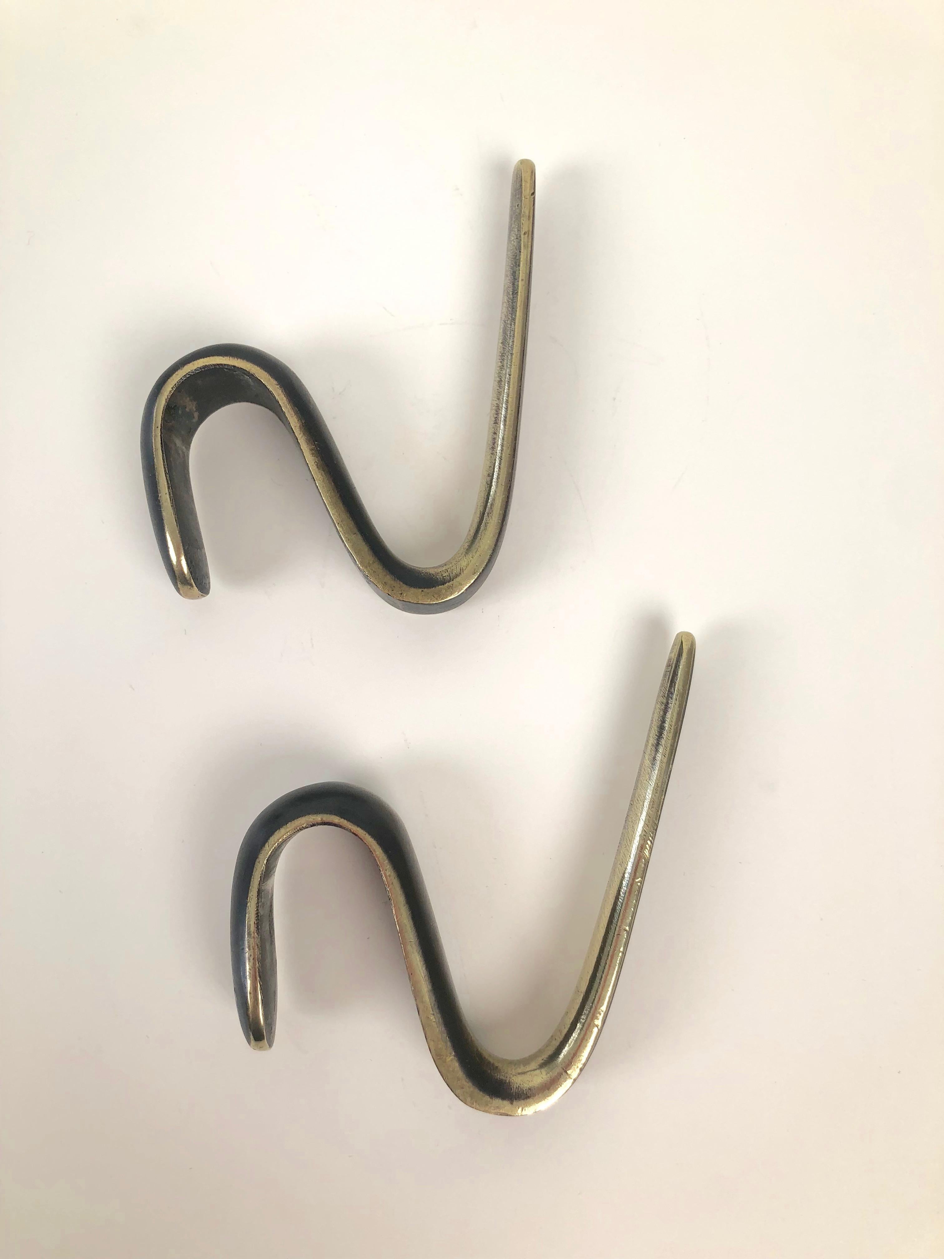 Two midcentury coat hooks in brass and black. Designed in the 1950s by Carl Auböck and manufactured in Austria, they have acquired a lovely patina from years of use.