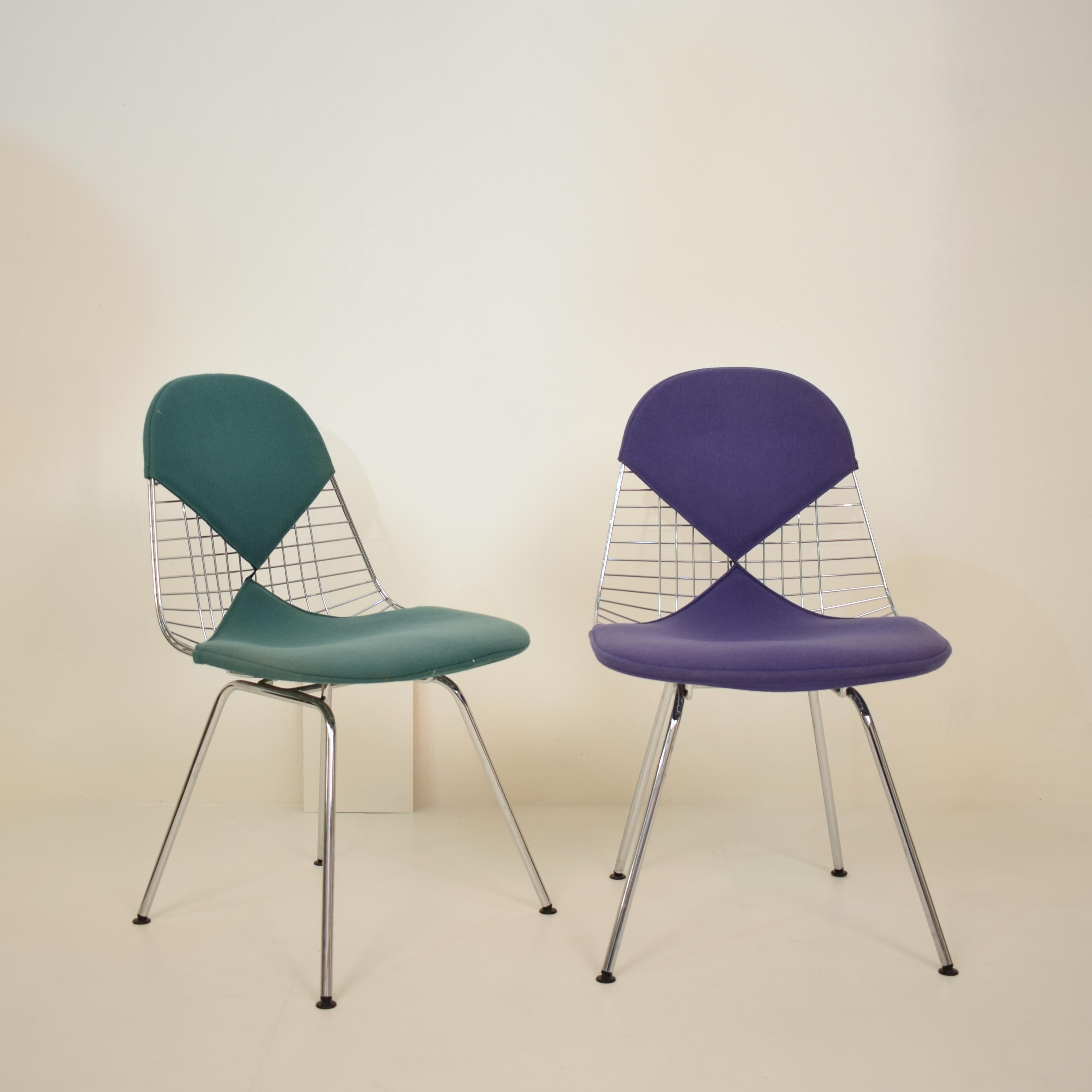 Set of two DKX-2 wire bikini shell chairs on X-bases with two different fabric covers designed by Charles and Ray Eames for Herman Miller. 
They are in beautiful vintage condition. The green and the purple bikini covers have been cleaned but have