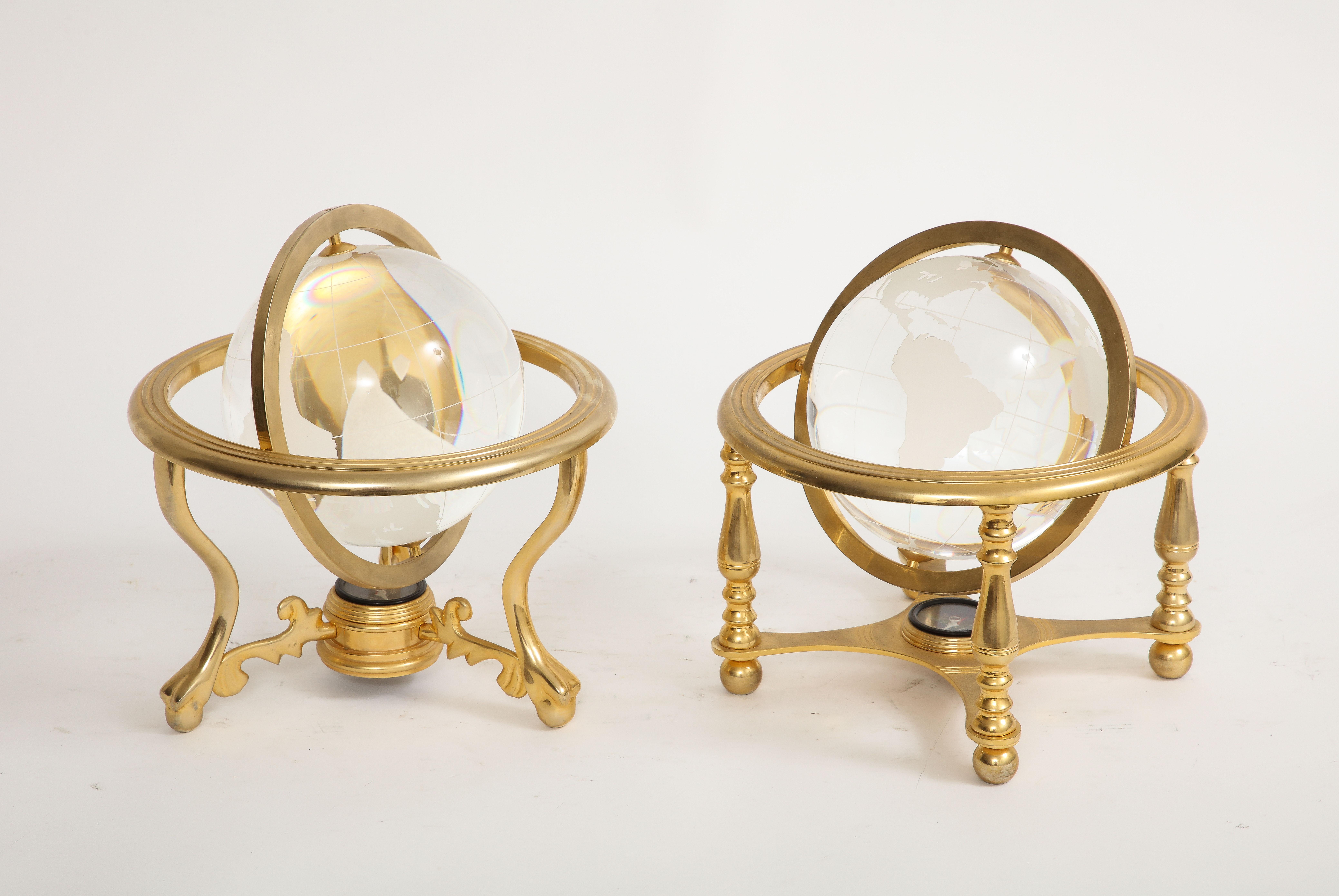 Two Mid-Century Modern French gilt bronze mounted crystal models of globes. Each with a classical globe style enhanced with a modern twist. The bronze mounts are all gilt and in the bottom center of each globe is a compass. The crystal globe balls
