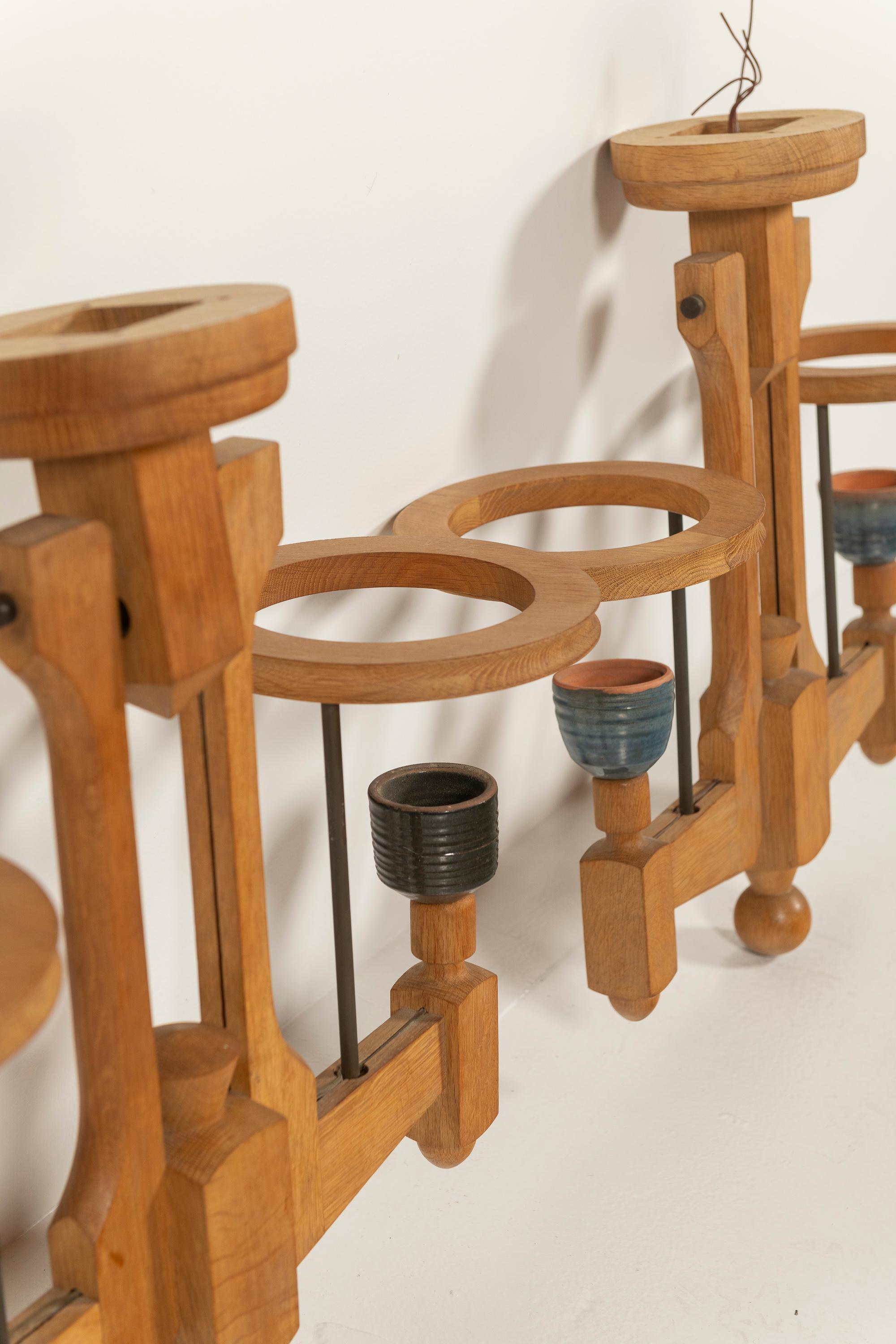 Pair of Mid-Century Modern oak and ceramic chandeliers by Guillerme & Chambron, 1960s. These elegant fixtures are in good condition and ready for installation. The ceramic bowls, crafted by Boleslaw Danikowski, add a distinctive artistic touch to