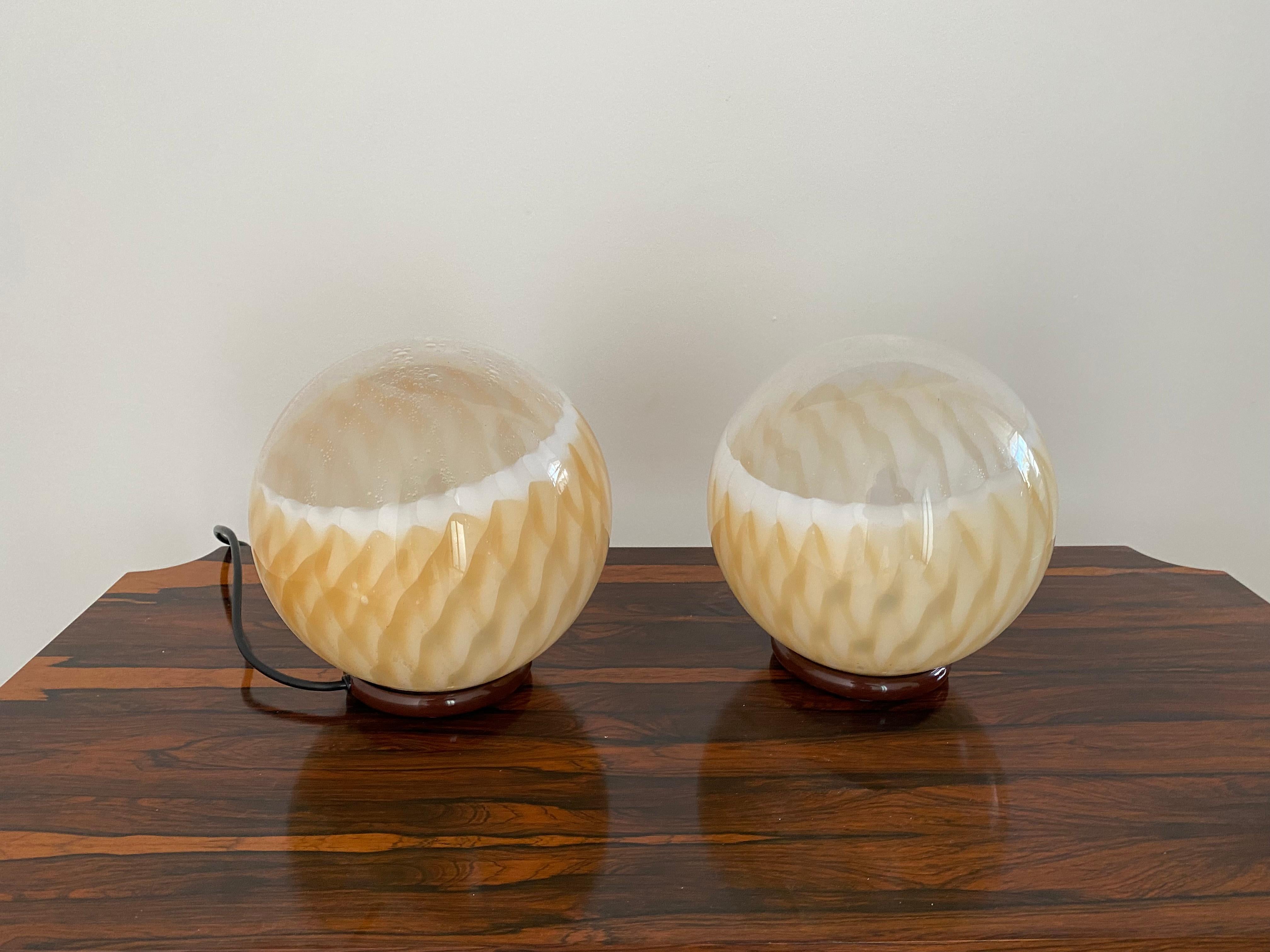 Space age one-light table lamps attributed to Mazzega, circa 1970.
Manufactured in a pattern of mottled orange, clear and white Murano glass and a brown lacquered metal base.
Priced Individually.
They're both the same size.