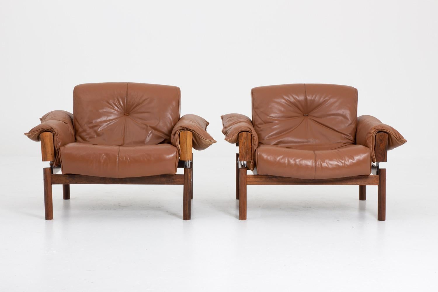 A pair of lounge chairs by Percival Lafer, Brazil.
These chairs consist of a rosewood frame upon which the cushions rest. The cushions are upholstered in brown leather with buttons of rosewood on the seating and backrest. The armrests are held in