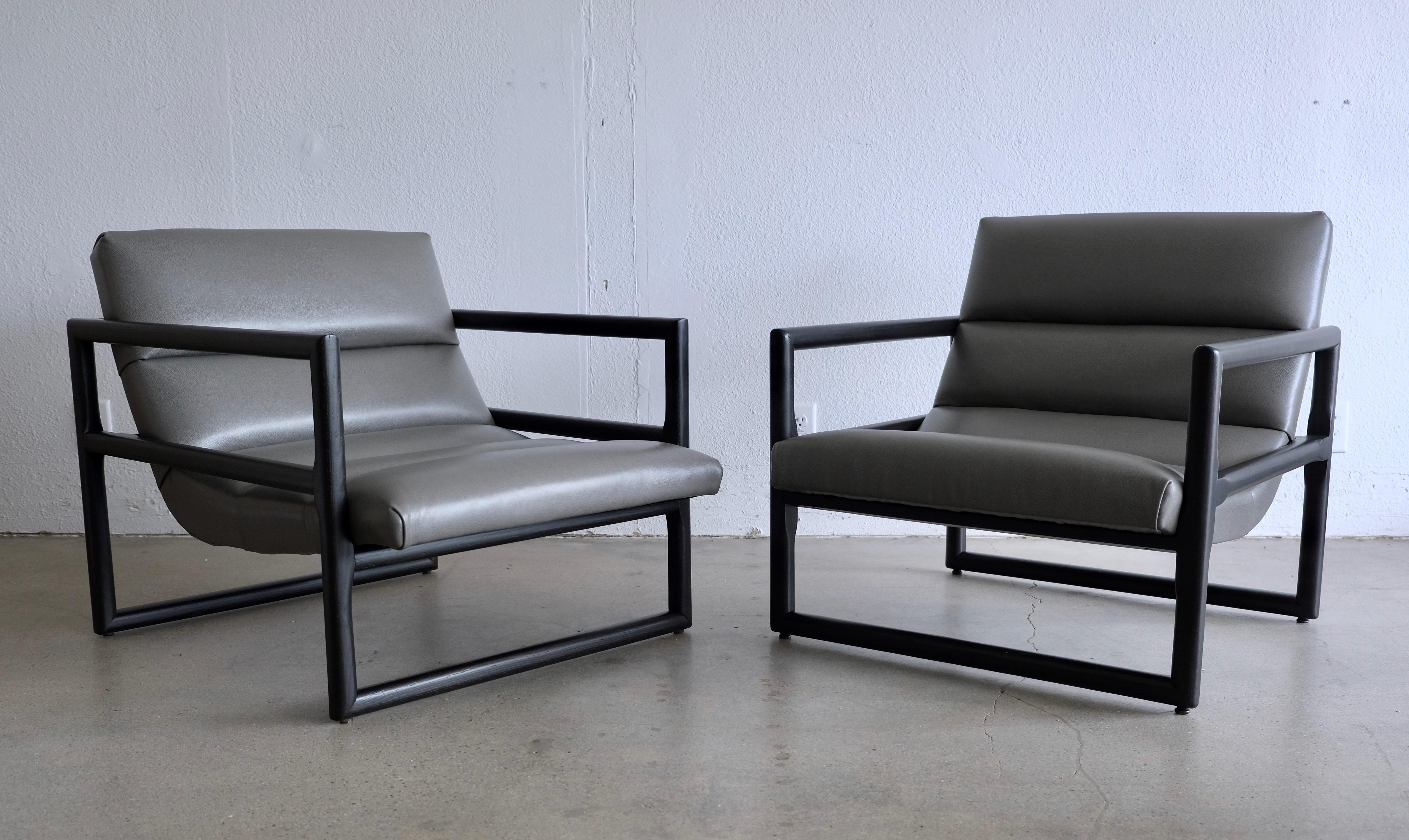Two Milo Baughman scoop lounge chairs that have been completed redone. The solid oak frames have been ebonized black and the upholstery has been covered in a subtle pebbled gray leather. The chairs have differences so they don't make an exact pair.