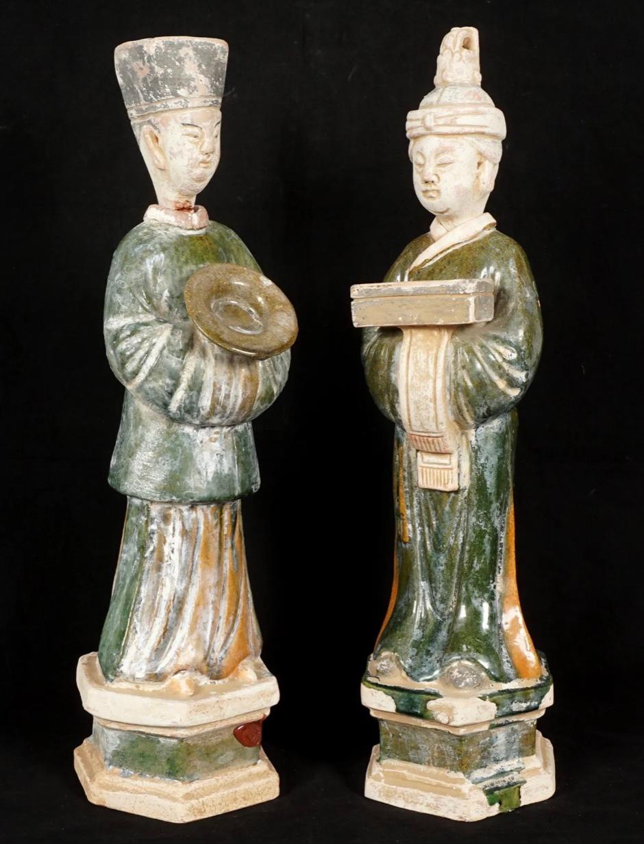 Two Chinese Ming style sancai polychrome glaze terracotta pottery figures of Chinese dignitaries in glazed green and ocher terracotta on hexagonal bases and removable heads. The man holding a bowl, the woman a box. Red wax export seal on base of man.