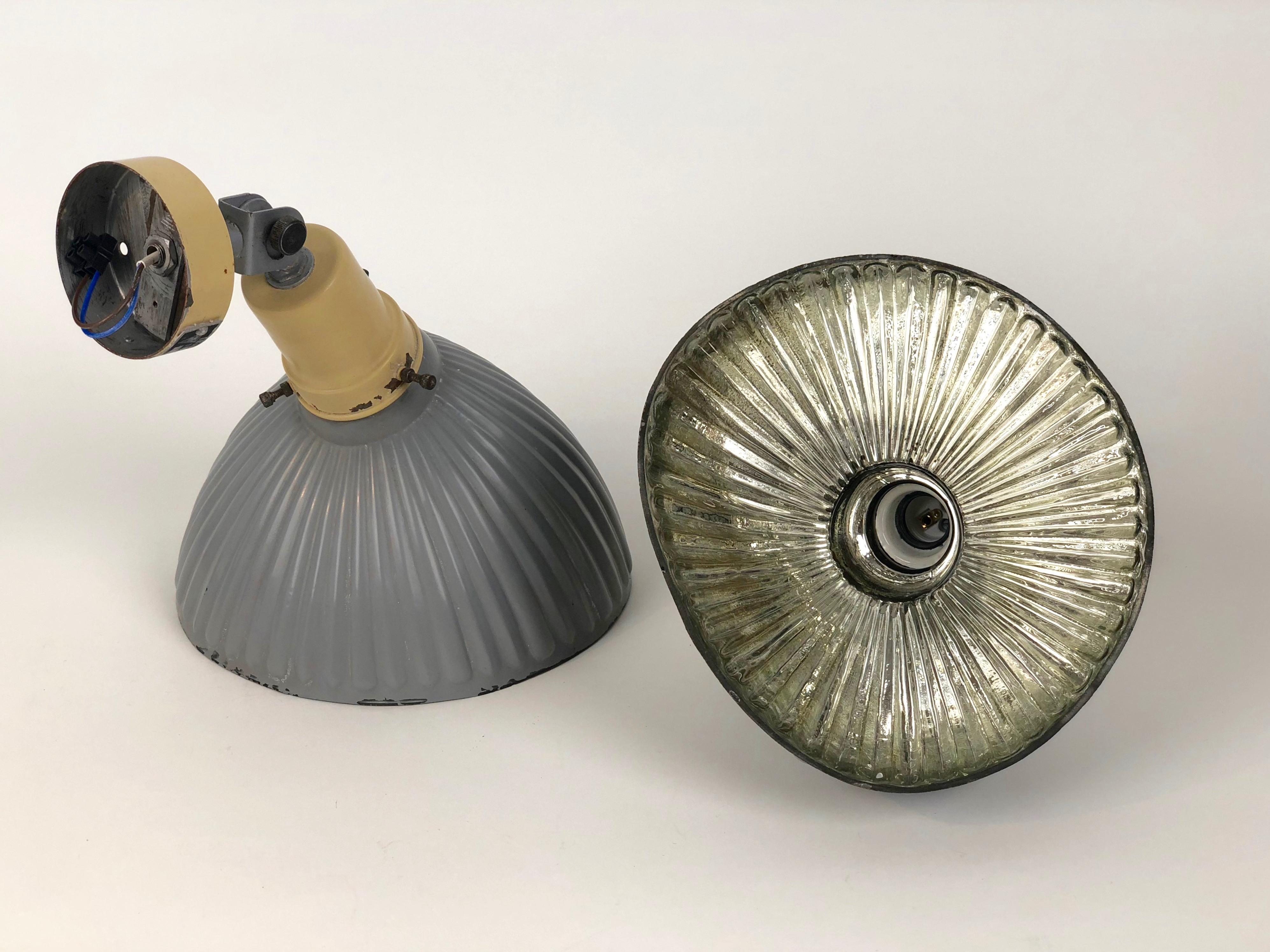 A pair of industrial, wall mounted, mirrored, glass wall lamps, produced by Instala Decin from the Czech Republic. Produced in the 1950s,
The glass shades have a fluted form with a reflective mirrored surface on the inside. Outside, the glass