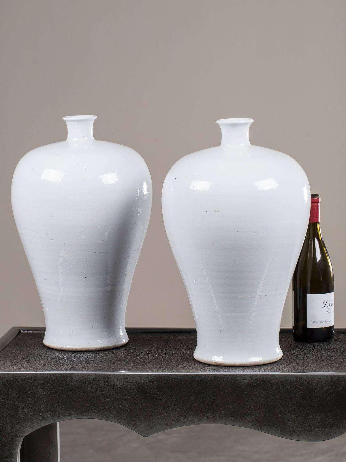 A set of two large handmade modern Chinese white porcelain vases in the famous Mei Ping shape. Please be sure to enlarge the photographs to see the slightly ribbed surface of each vase indicative of being turned by hand on a potter's wheel. The term