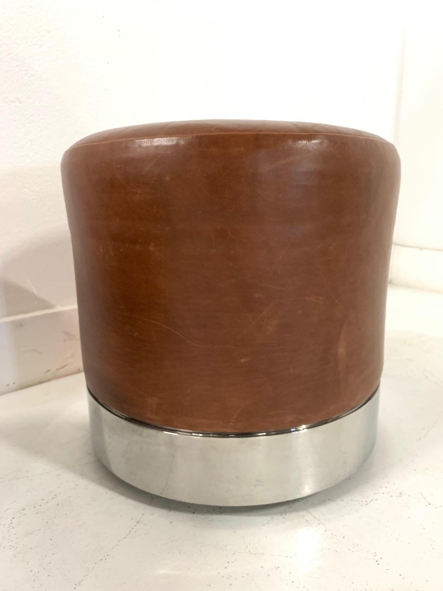 Two modern leather and polished chrome stools. Both stools have casters with a gently worn, cognac leather upholstery.