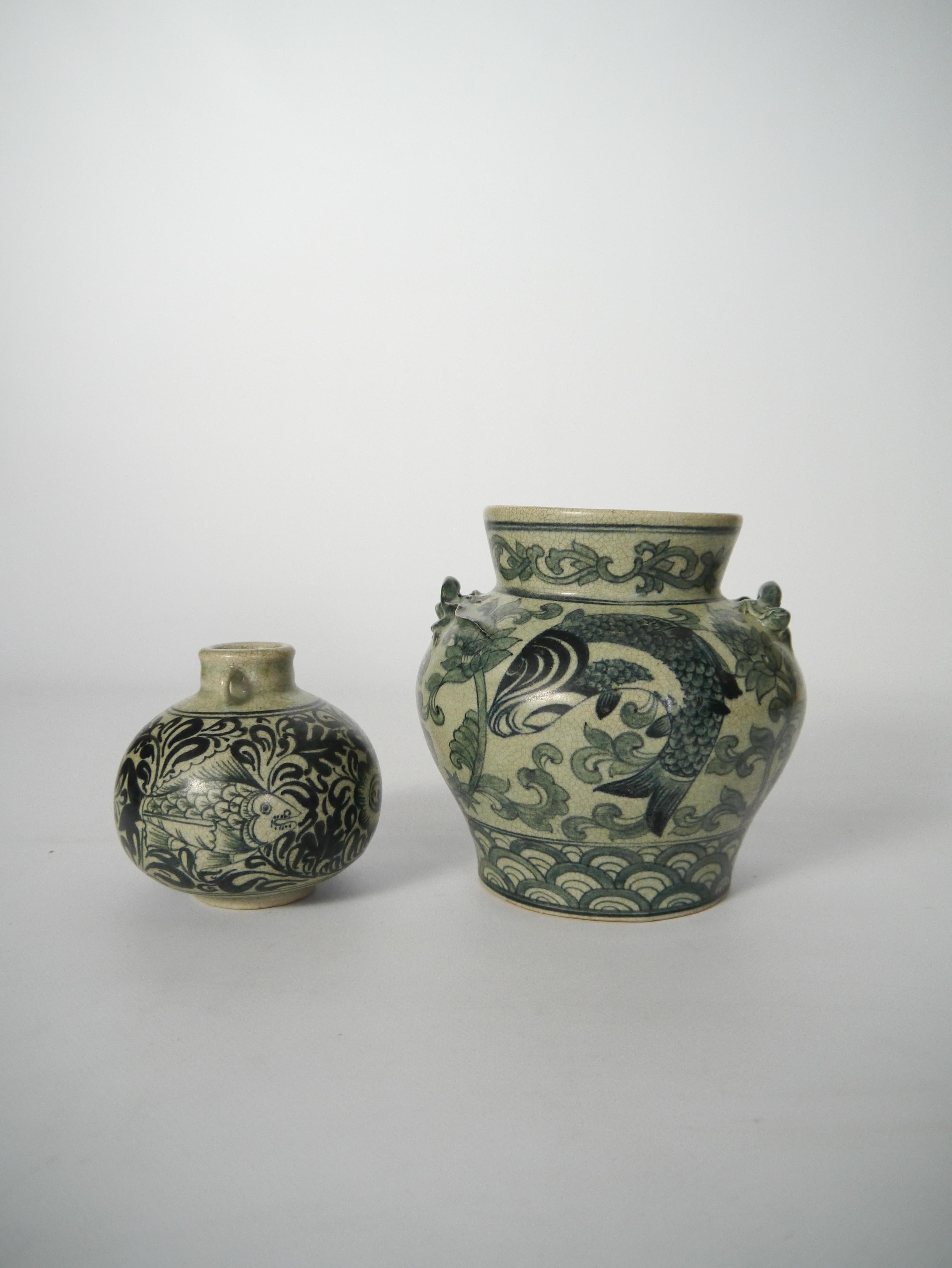 Two patinated ceramic vases, with beautifully crackled glaze, sharp graphic monochrome chinoiserie pattern consisting of fishes / floral branches. Both vases resembles an amphora vase, the bigger with two exquisitely executed handles in shapes of