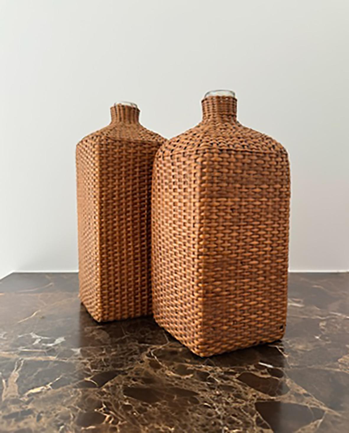 Due bottiglie di vino in vetro soffiato a bocca di Boemia in una gabbia di rattan. Realizzato in Francia nel 1900 circa.

Queste due bottiglie in vetro soffiato a bocca, racchiuse in un elegante cesto in rattan di stile boemo, emanano una bellezza e