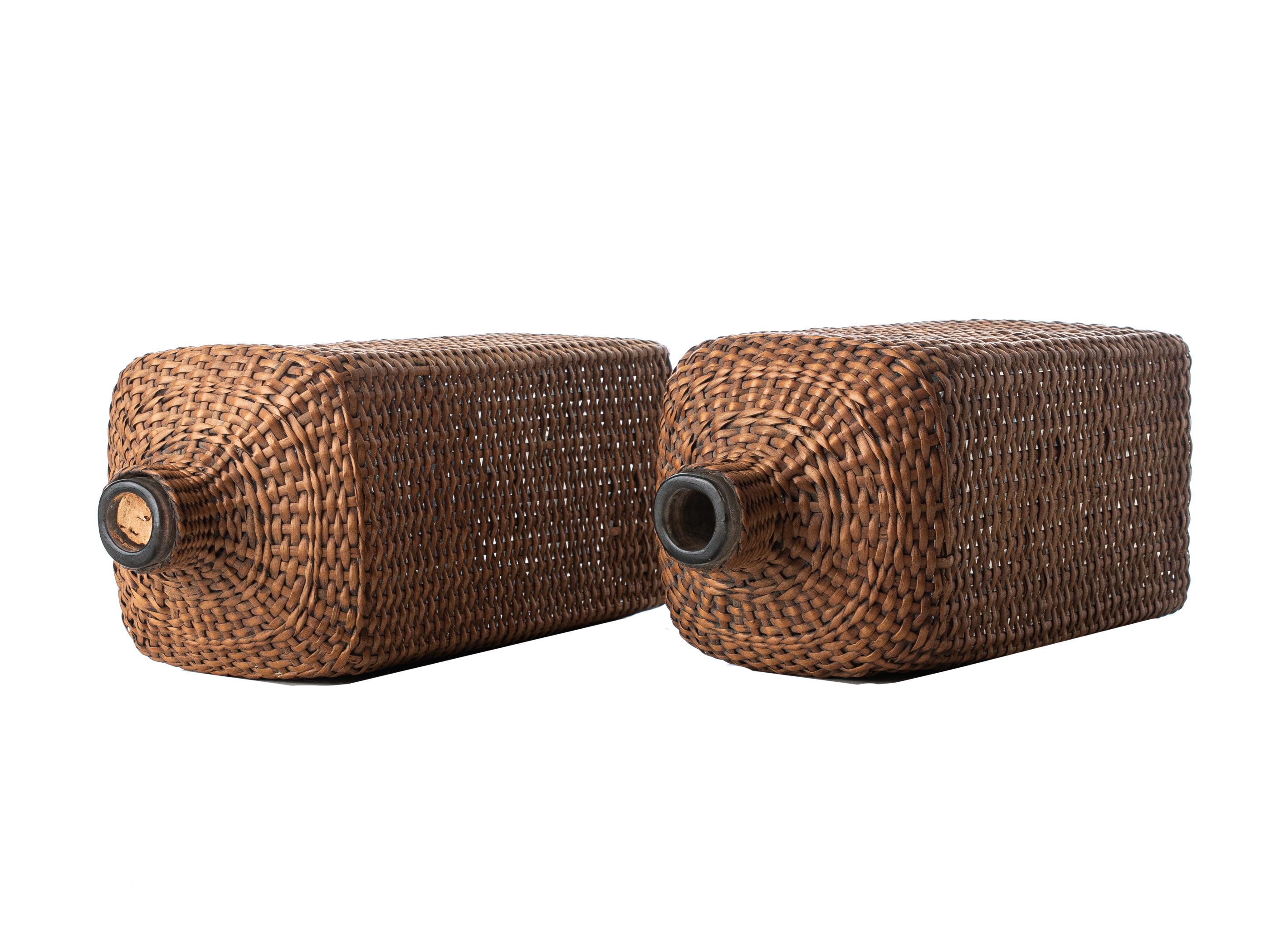 Francese Due bottiglie di vino in vetro soffiato a bocca in una gabbia di rattan, Francia, circa 1900. in vendita