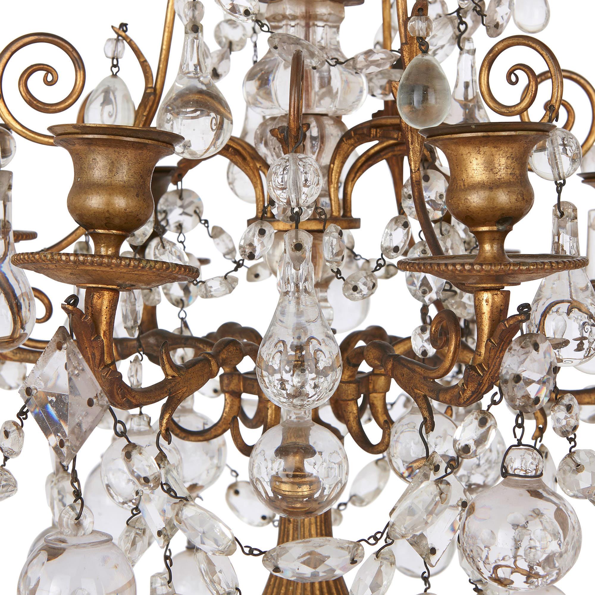 These two candelabra were created in France at the turn of thecentury, crafted from gilt bronze and fine cut glass. The candelabra stand on baluster-shaped, fluted gilt bronze stems, which are set on circular bases with beaded edges. Each
