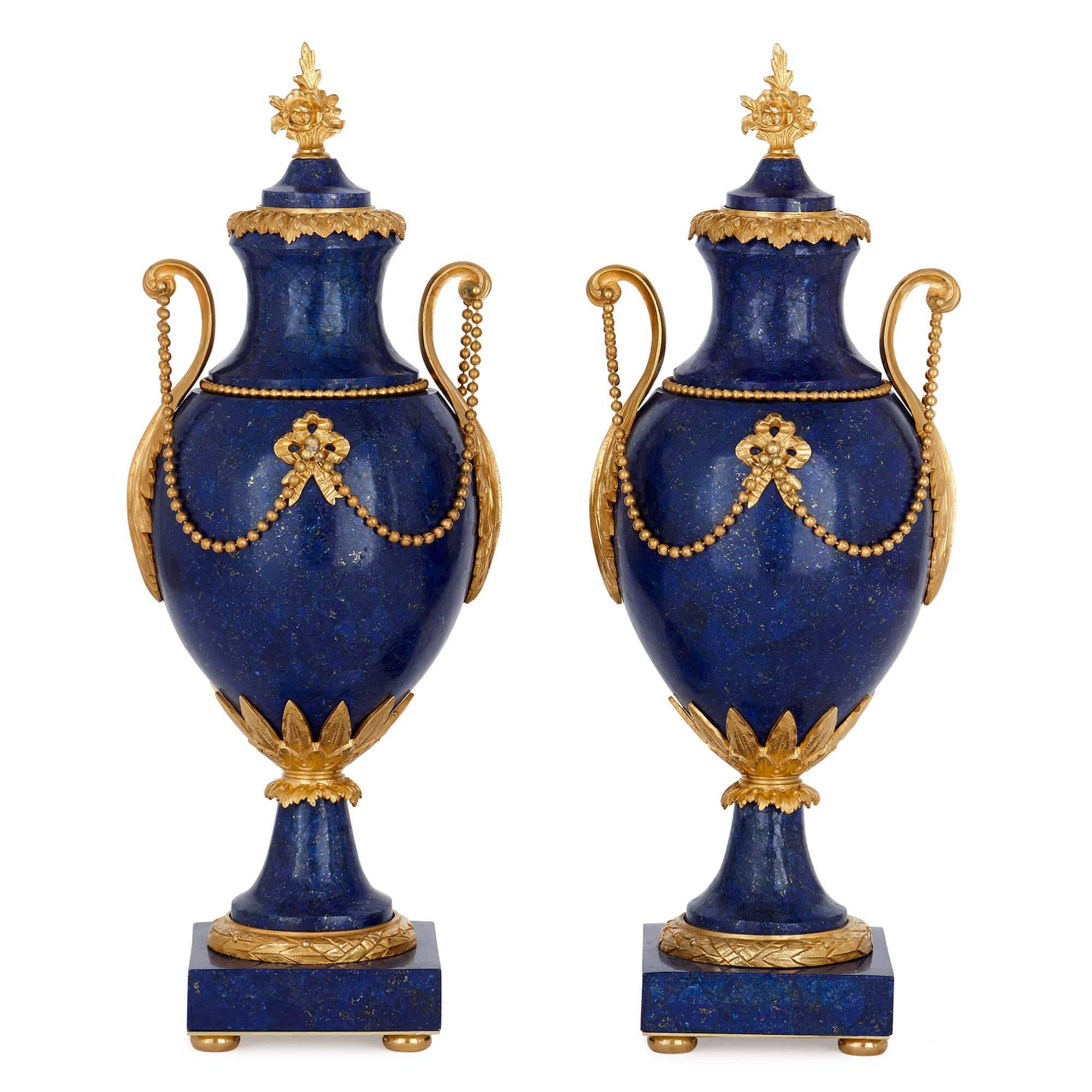 These exquisite vases are crafted in sumptuous materials, combining gleaming gilt bronze with the cool blue lapis lazuli. The vases date originally to the early 20th century, with the lapis lazuli veneer being a later addition. 

Of ovoid form,