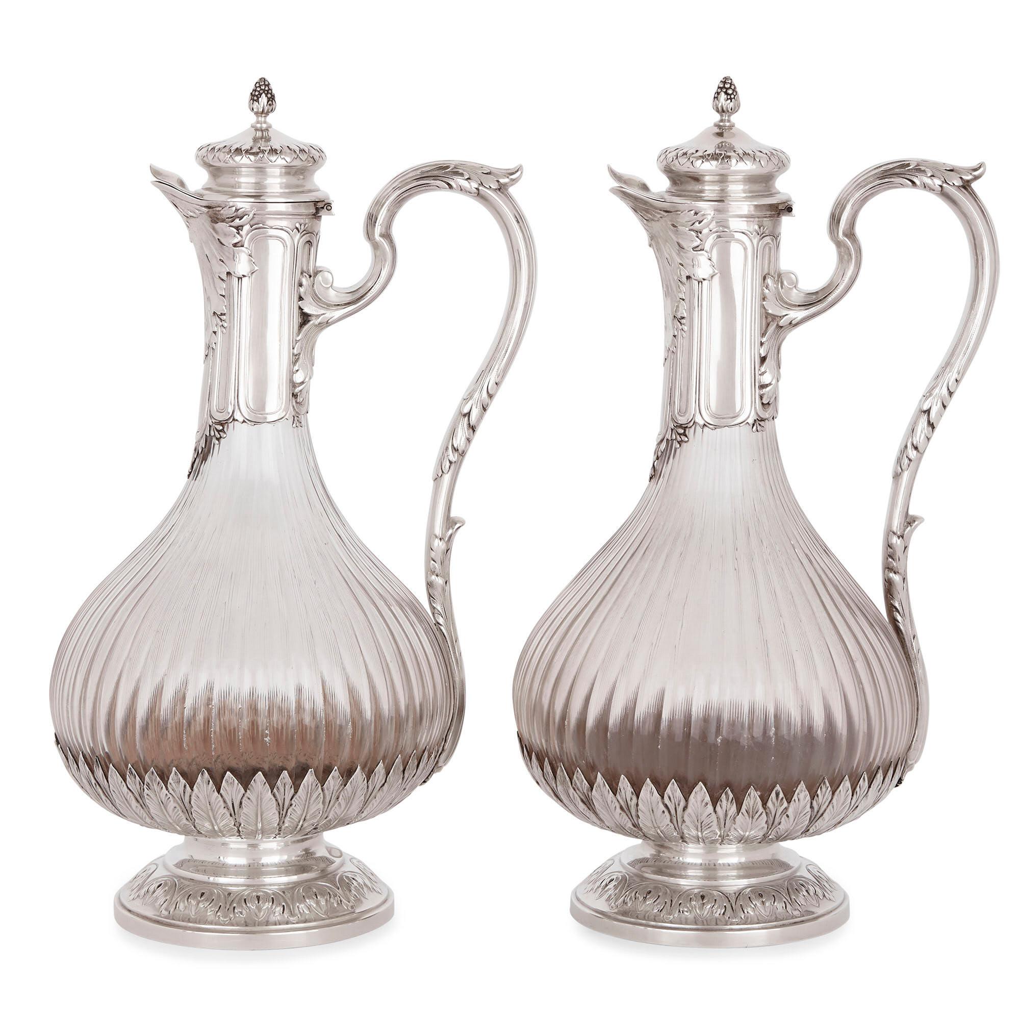 These claret (wine) jugs are exquisite pieces of antique French drinkware, which are designed in a refined and elegant neoclassical style. They are crafted from crystal glass and mounted with sterling silver. The jugs bear standard silver marks, as