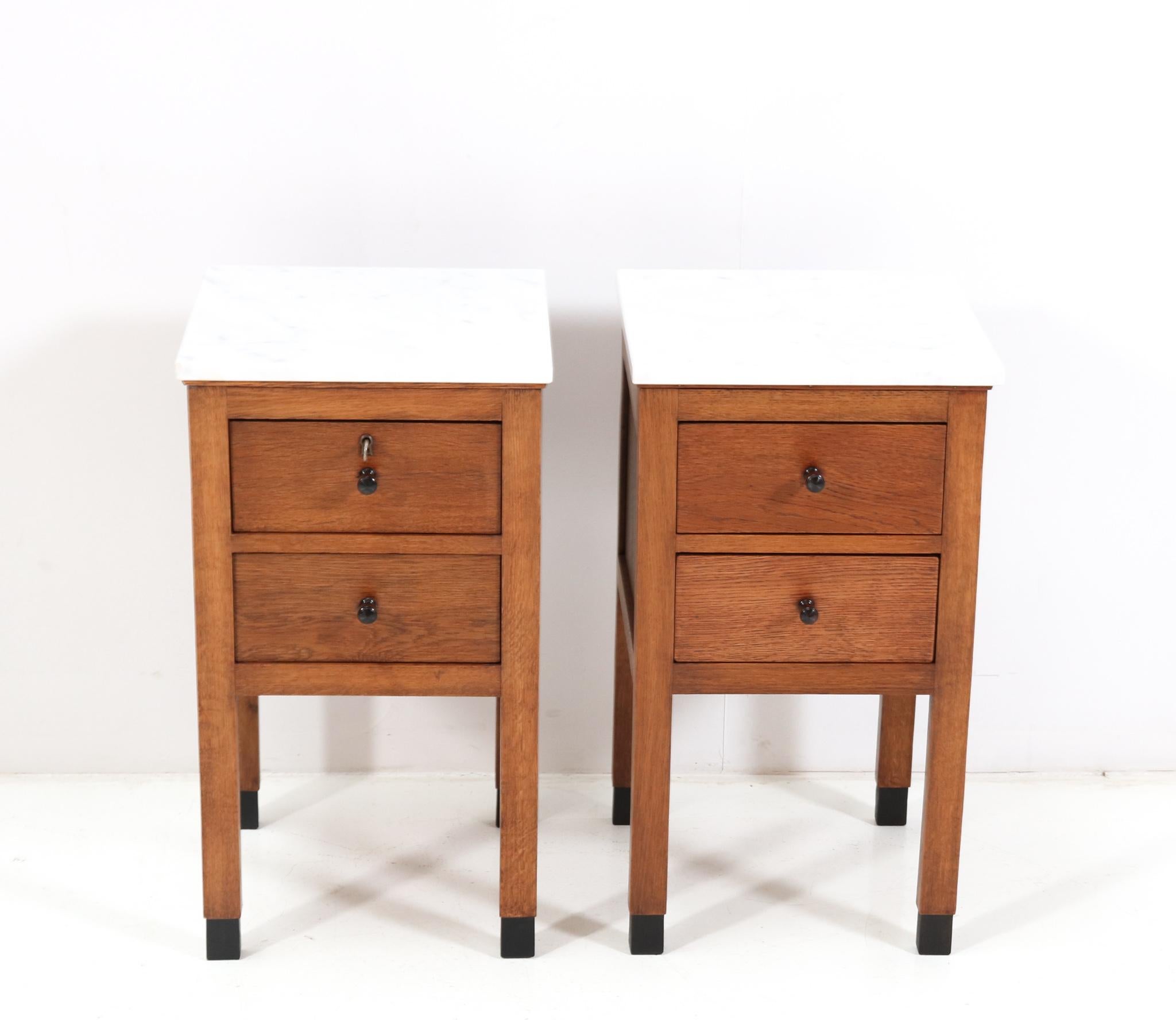 Amazing and rare pair of Art Deco Amsterdamse School nightstands or bedside tables.
Striking Dutch design from the 1920s.
Solid oak with original white marble tops.
Four original macassar ebony knobs on the four drawers.
This wonderful pair of