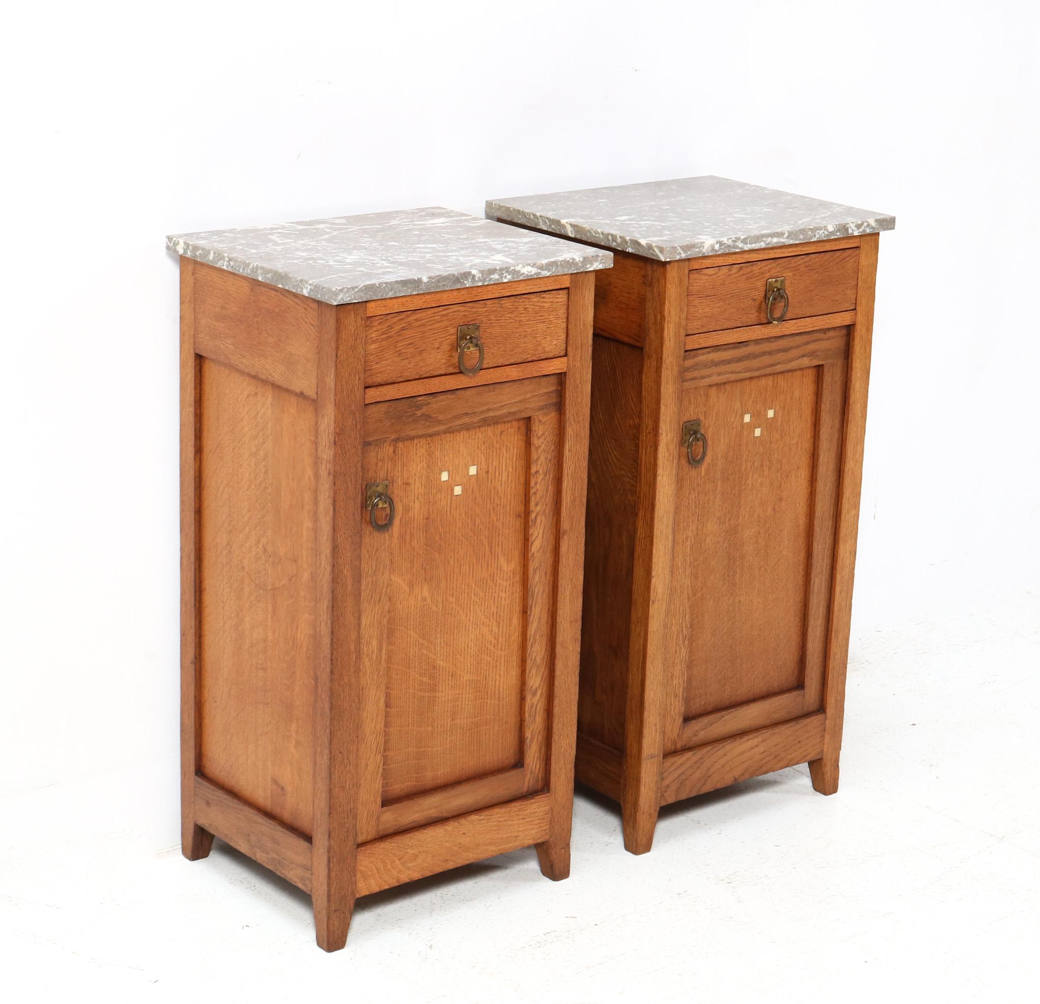 Stunning and rare pair of Art Nouveau Arts & Crafts bedside tables or nightstands.
Striking Dutch design from the 1900s.
Solid oak with original brass handles on doors and drawers.
Two original multi-colored marble tops.
This wonderful pair of Art