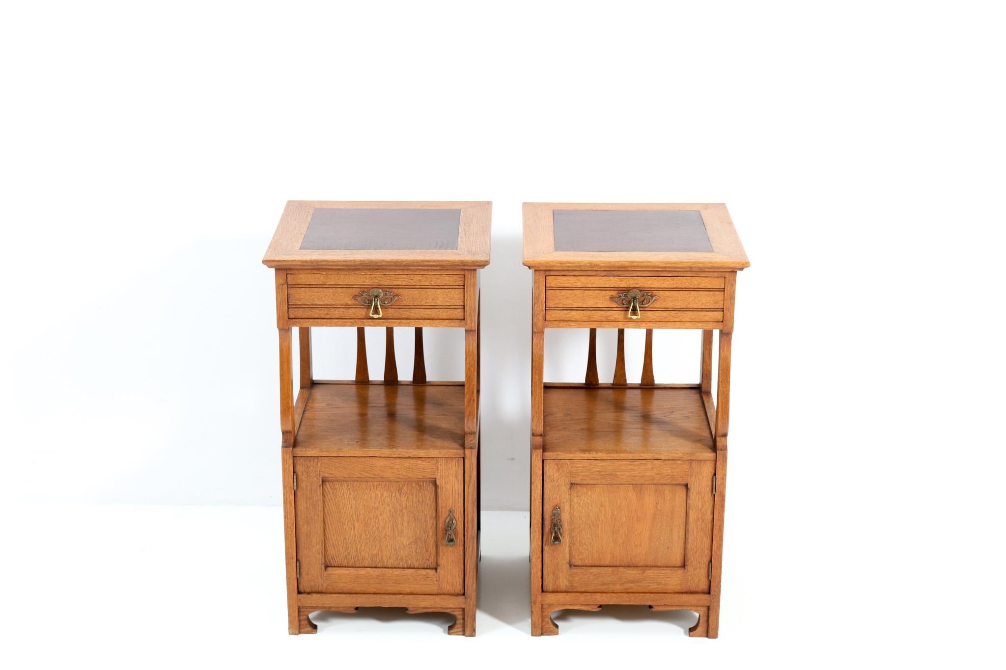 Stunning and rare pair of Art Nouveau Arts & Crafts nightstands or bedside tables.
Striking Belgium design of the 1900s.
Solid oak with original brass handles on drawers and doors.
The tops are inlaid with walnut.
The design of this wonderful