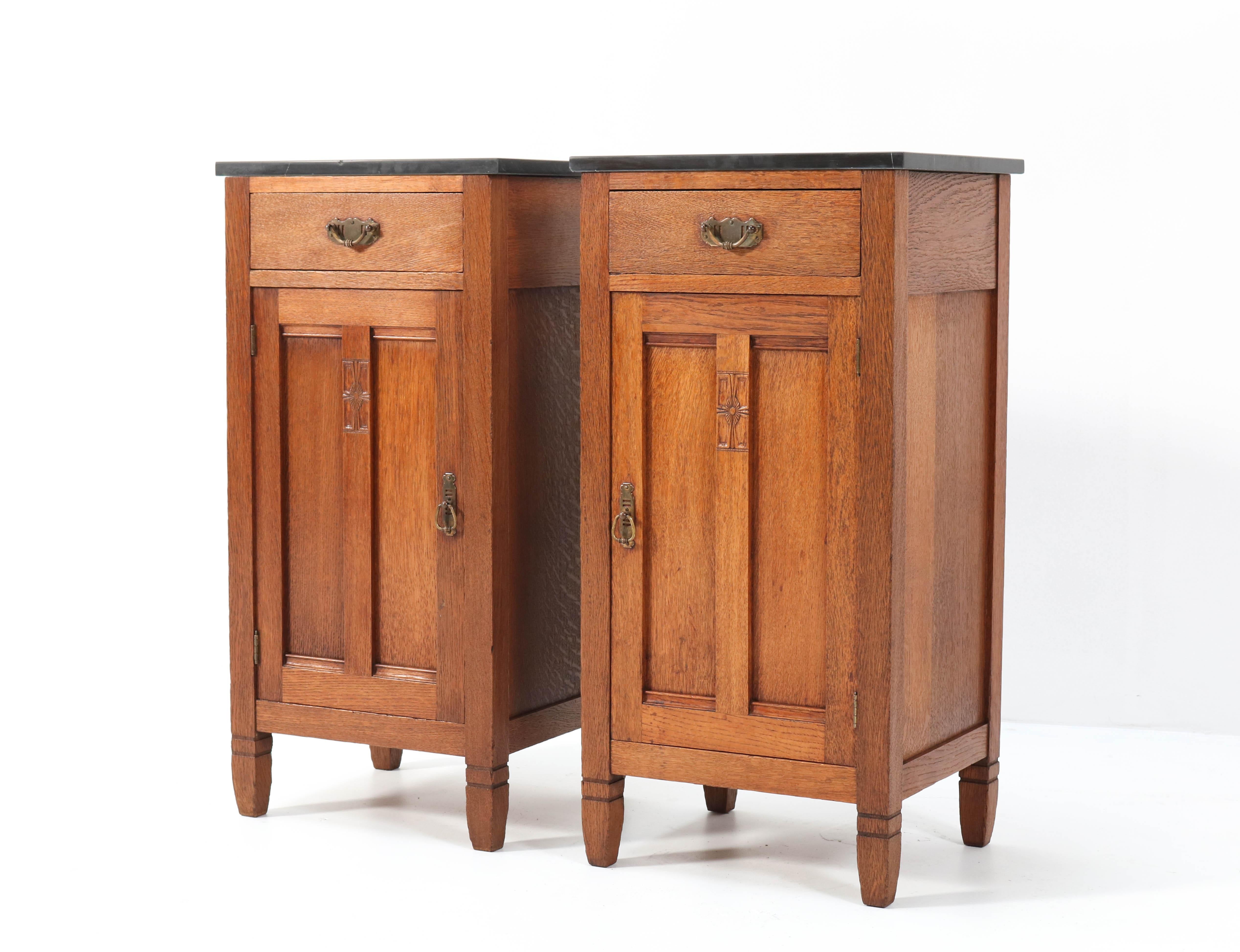 Magnificent and rare pair of Arts & Crafts Art Nouveau nightstands.
Design by H. Pander & Zonen.
Striking Dutch design from the 1900s.
Solid oak with black marble tops.
Original brass handles on doors and drawers.
Marked with original