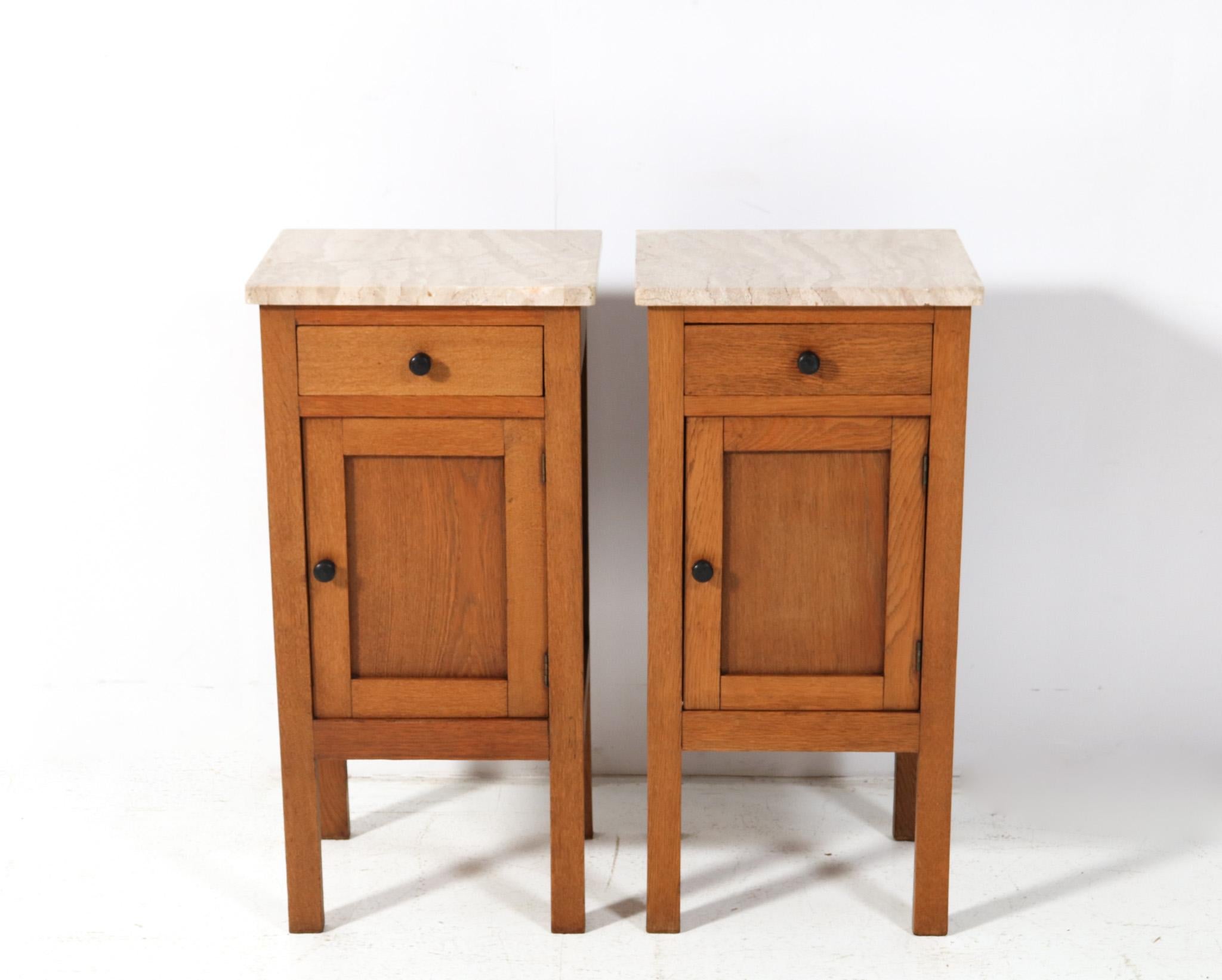 Stunning and elegant pair of Arts & Crafts Art Nouveau nightstands or bedside tables.
Striking Dutch design from the 1900s.
Solid oak base with original solid ebony knobs on doors and drawers.
Two original multi-colored marble tops.
This wonderful