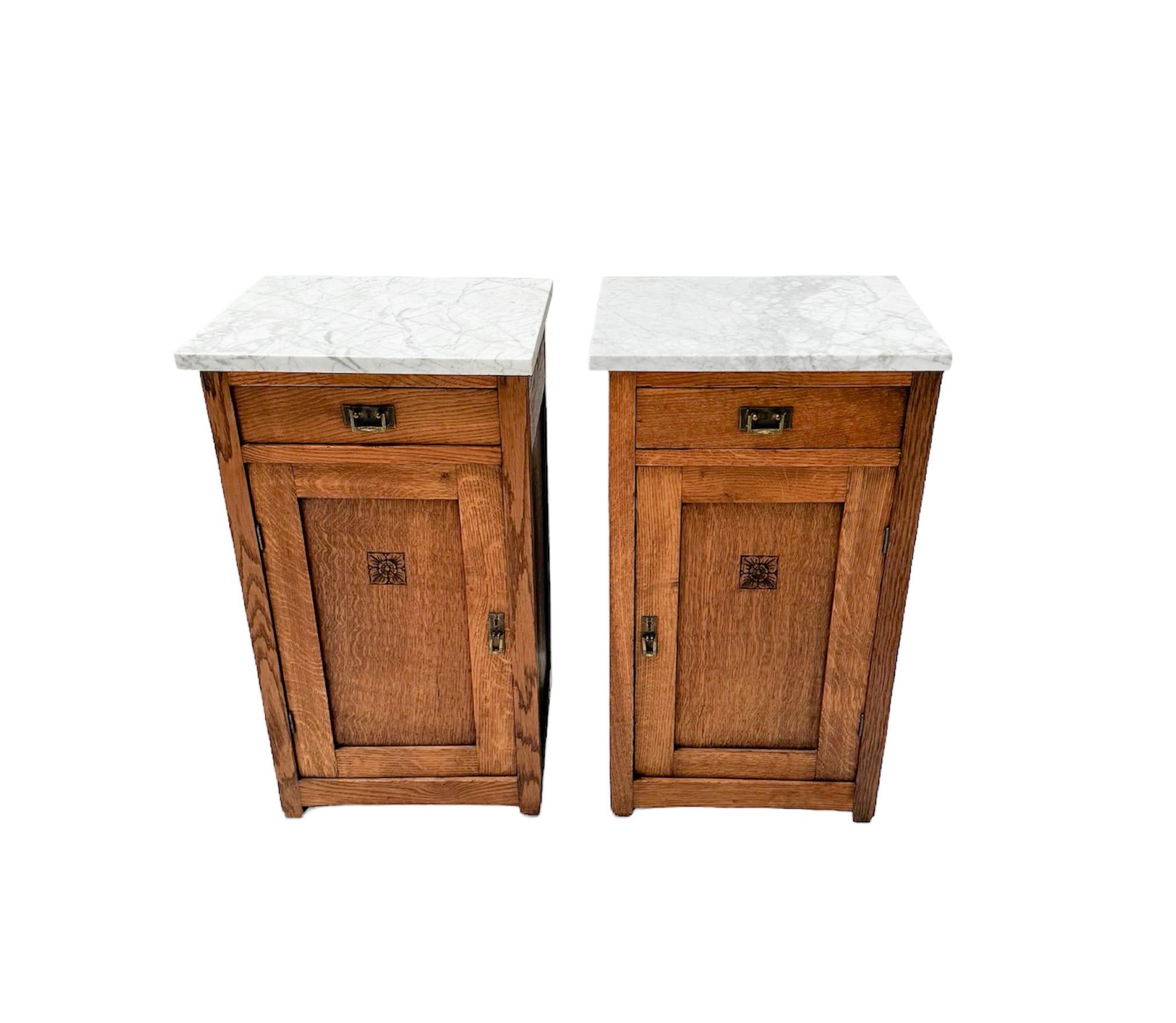 Stunning and elegant pair of Arts & Crafts Art Nouveau nightstands or bedside tables.
Striking Dutch design from the 1900s.
Solid oak bases with original patinated brass handles on doors and drawers.
Original white and grey colored marble tops.
This
