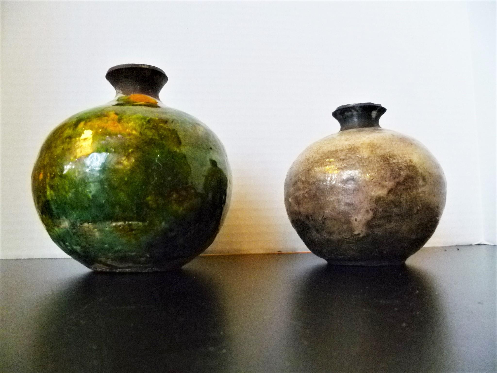 Early 1960s Weed Pots, two pieces of organic modern Studio Pottery signed E. Jensen. Done in the Western Raku method. The smaller brownish tone with the tell tale crackle of Raku firing, the larger green vessel seems to have been glazed over a Raku